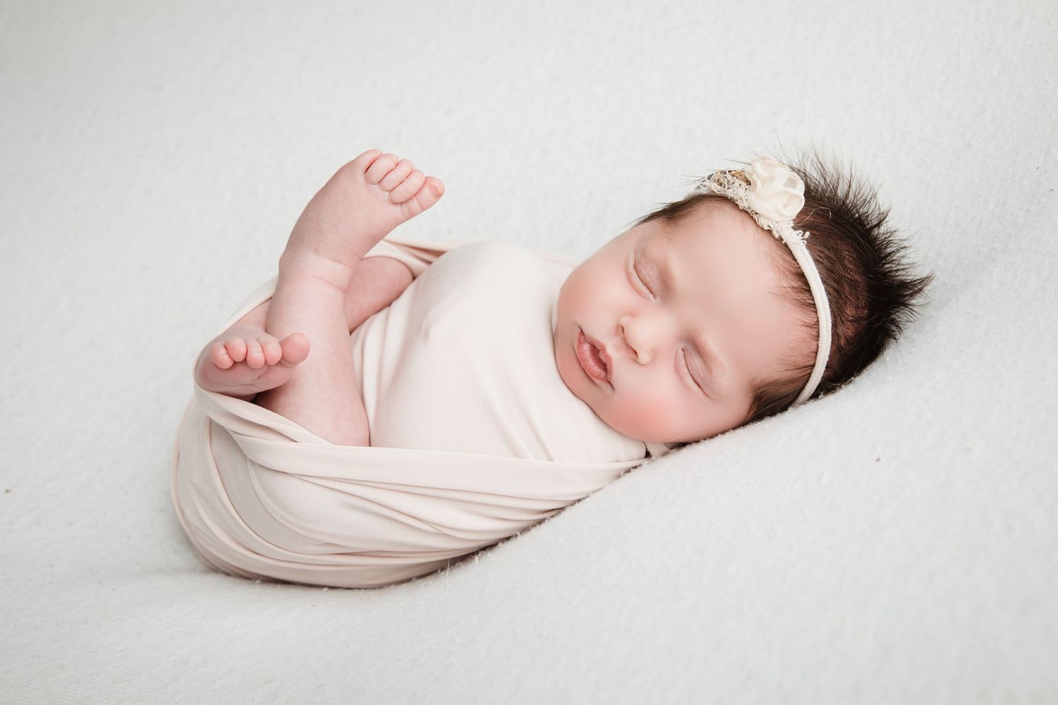 A series of newborn baby photographs showing peaceful sleeping poses in soft white wraps and blankets.