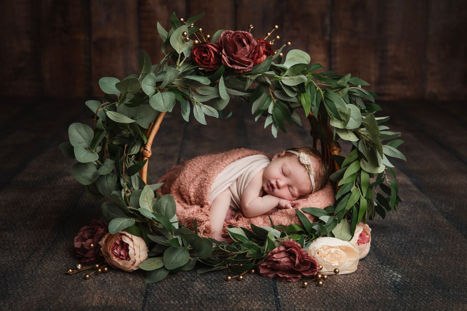 Artistic newborn photography collage with soft floral arrangements and greenery on dark wooden backdrop.