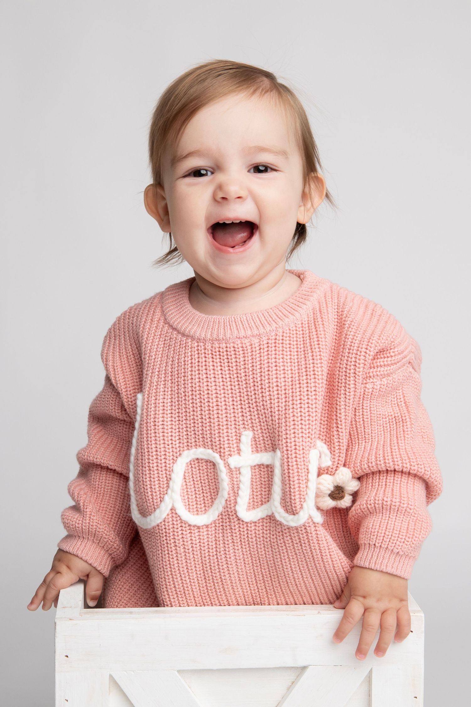 A series of expressive photos in a pink knitted sweater against a clean white backdrop.