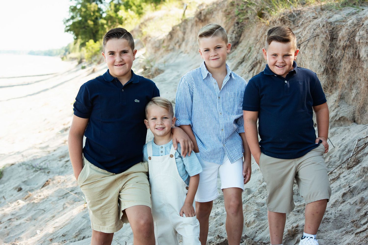 Family group posing together on sandy beach cliffs during summer photoshoot.