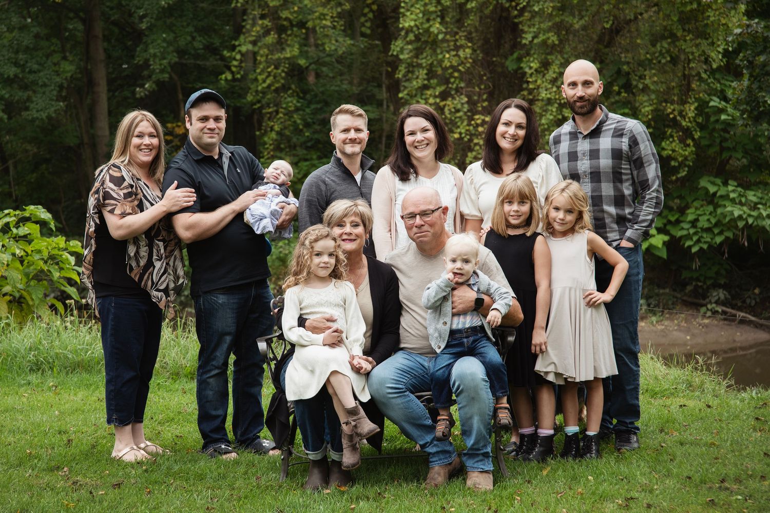 Large multi-generational family gathered for a portrait in a lush garden setting.