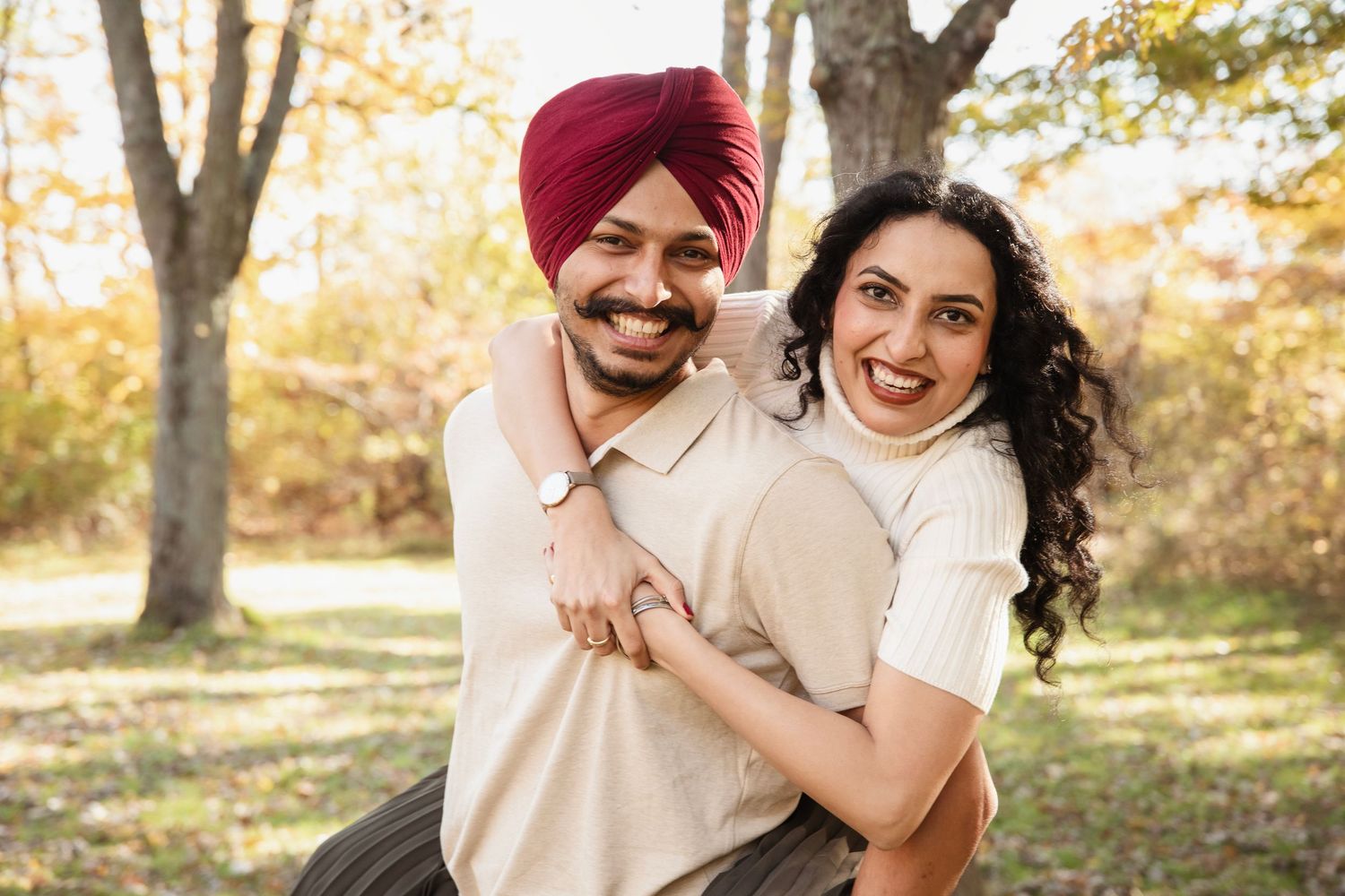 A couple shares joyful laughs while relaxing in a sunlit autumn forest.