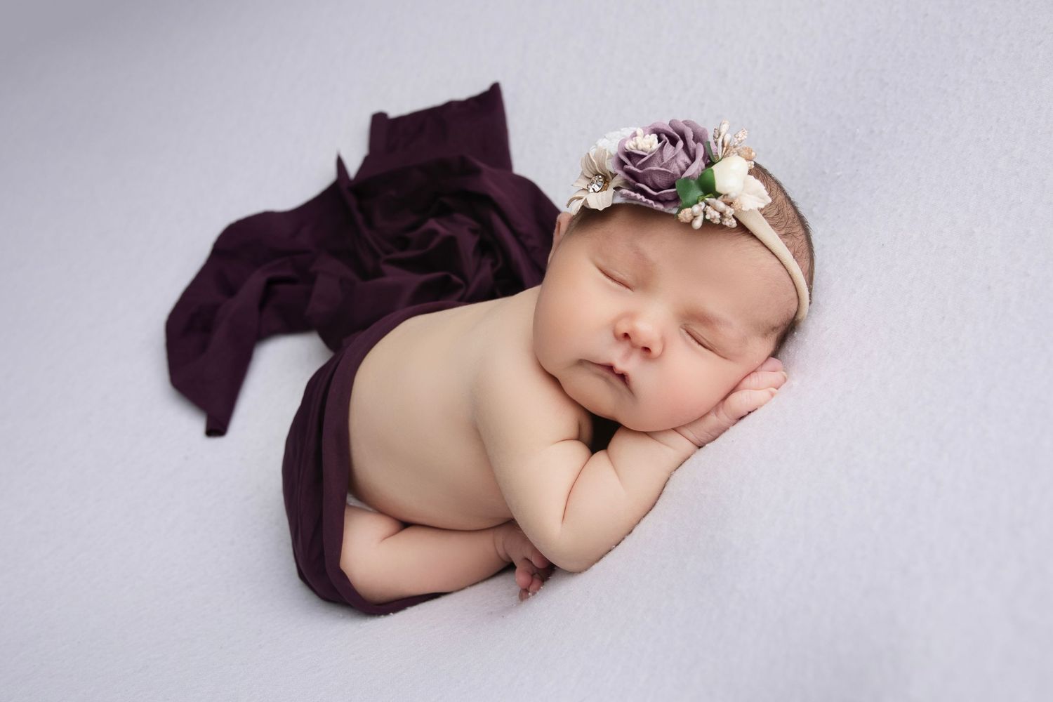 Creative newborn portrait series with baby posed on purple fabric backdrop.