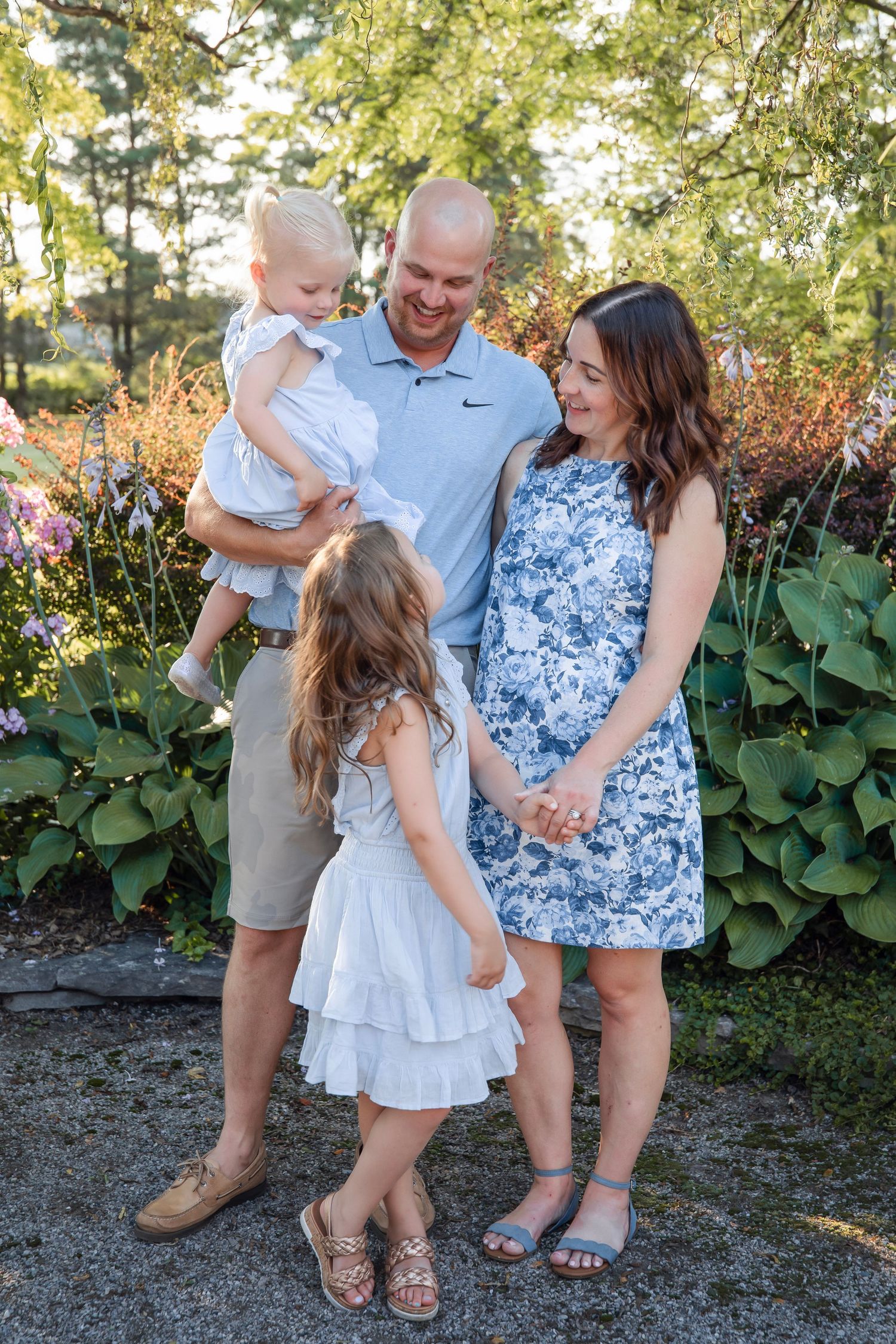 Family of four sharing joyful moment together outdoors against lush garden background.