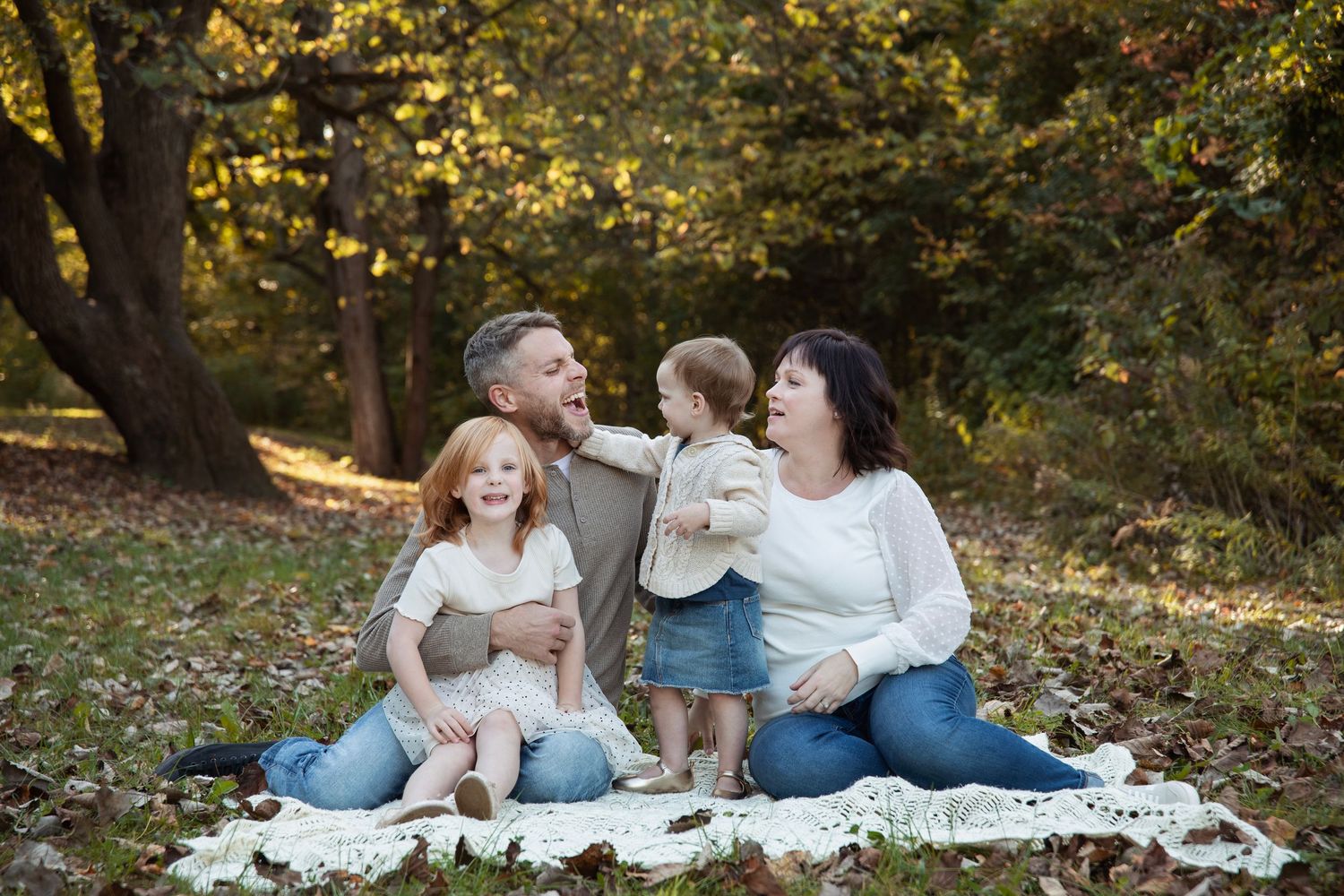 Family having a picnic and sharing tender moments on a blanket in a park.