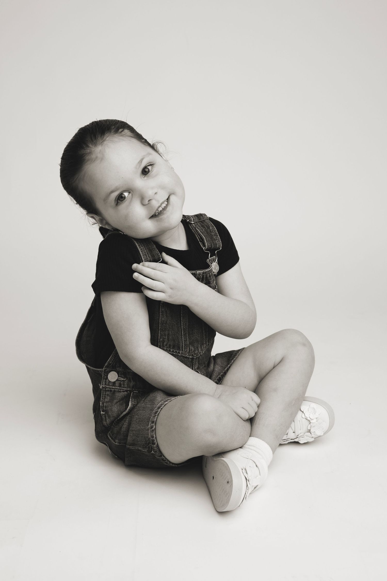 Black and white portrait series showing playful poses in casual denim outfit.
