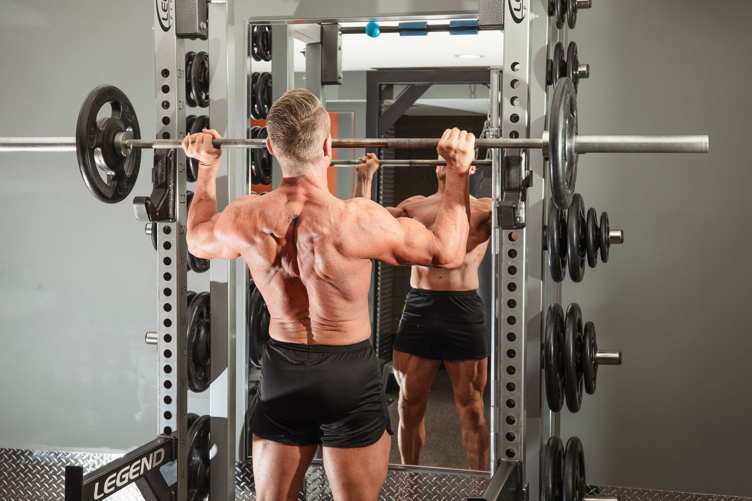 A person performs squats with a barbell in a modern gym setting using proper form and technique.