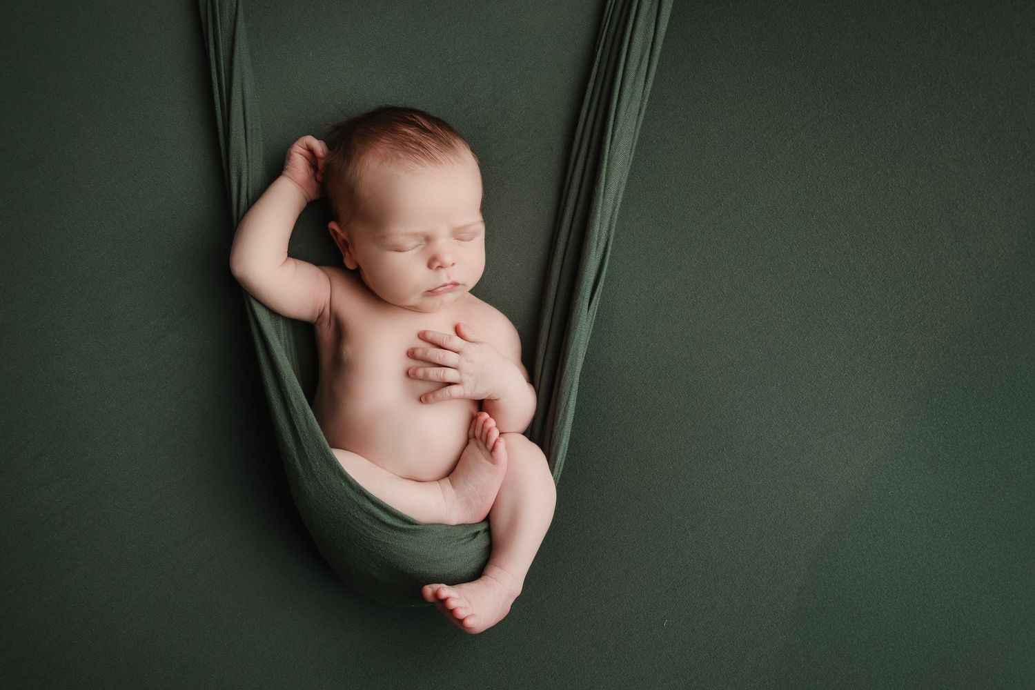 Series of minimalist newborn photos showing varying poses against a dark green textured backdrop.