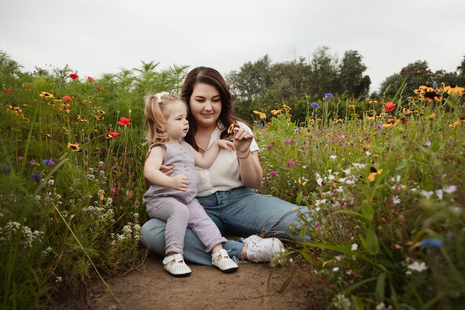 Mother and child sitting together in a colorful wildflower garden.