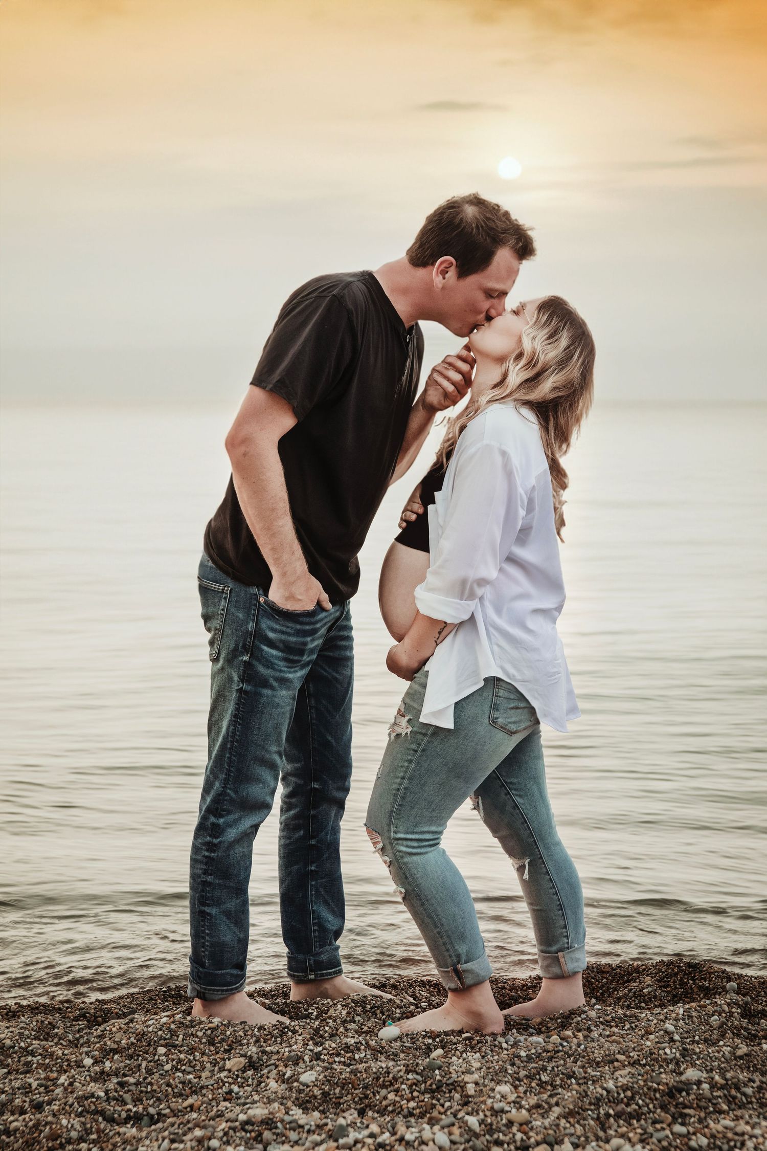 A romantic beach photoshoot of a couple sharing an intimate moment at sunset.