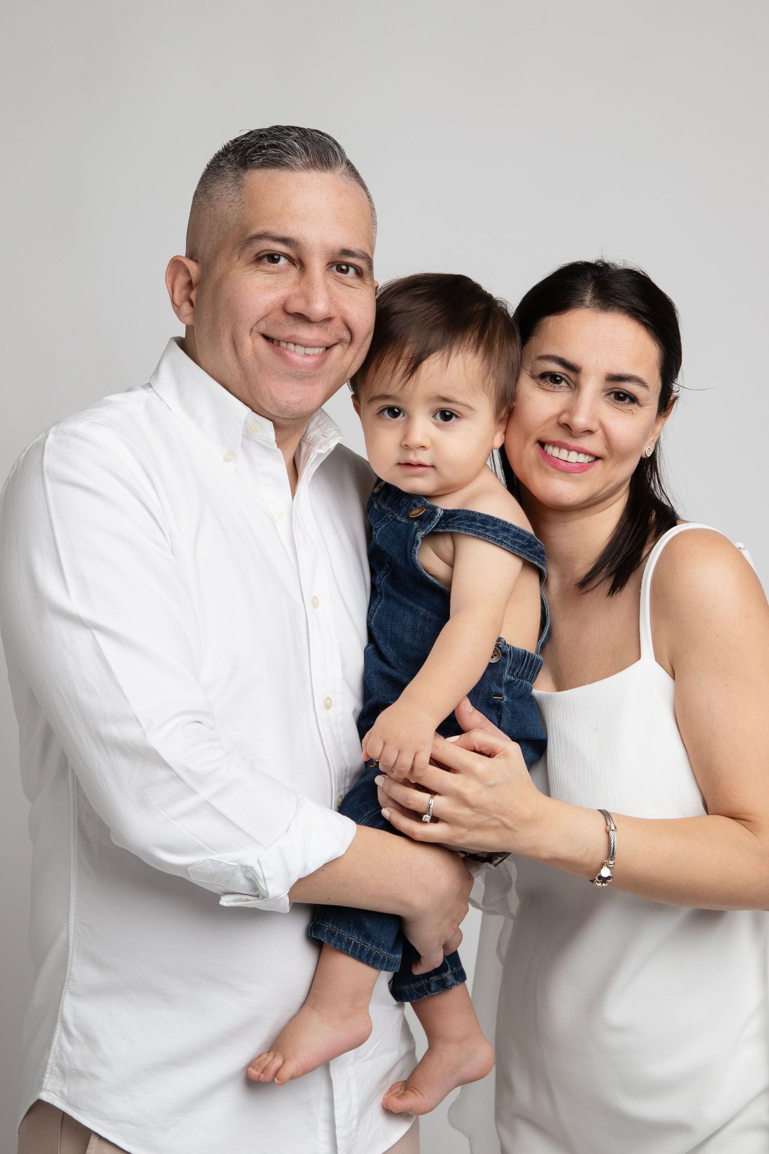 Family portrait series in white studio setting showing loving embraces and joyful moments together.