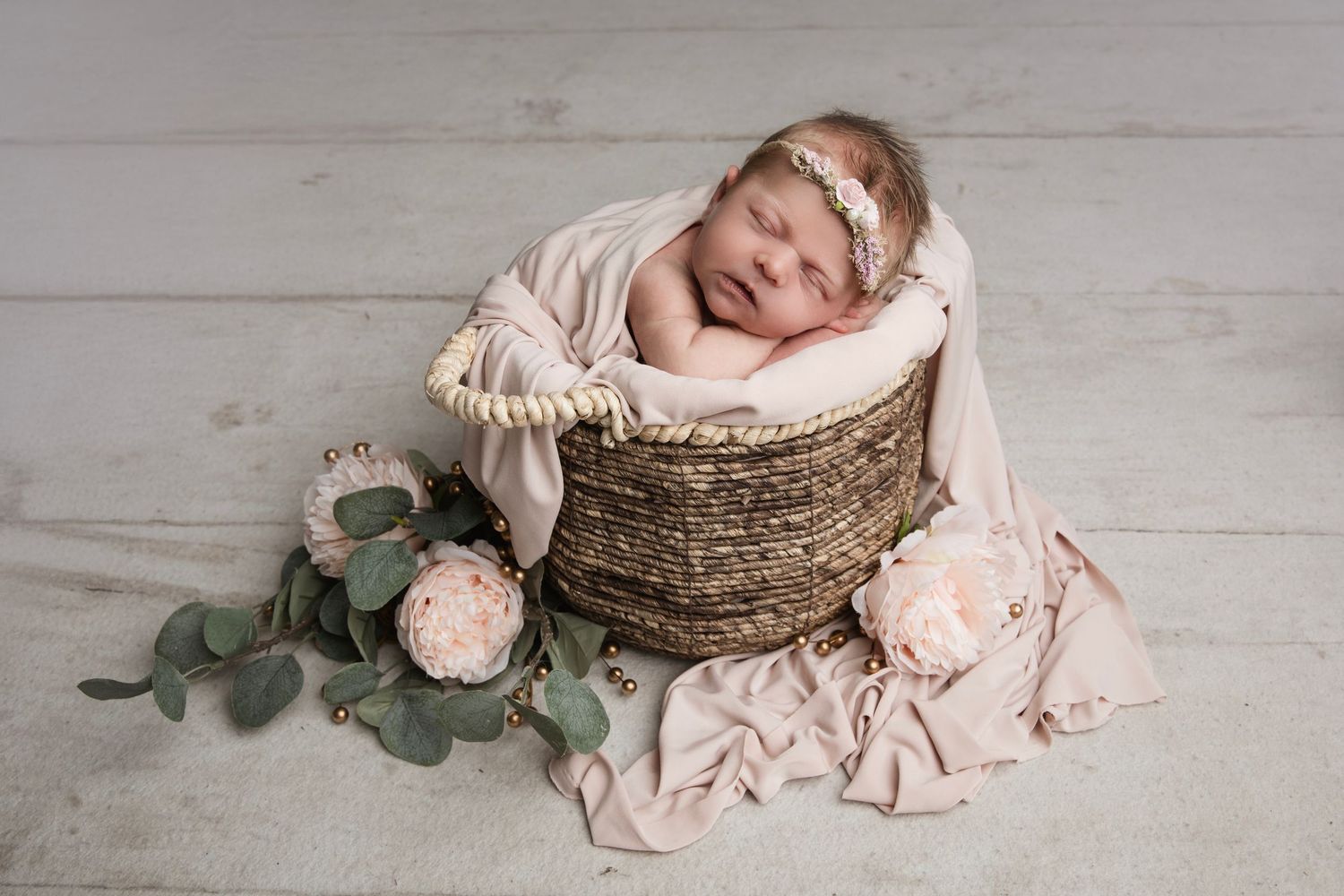 A decorative rustic wreath and floral arrangement on white wooden background with pink accents and eucalyptus.
