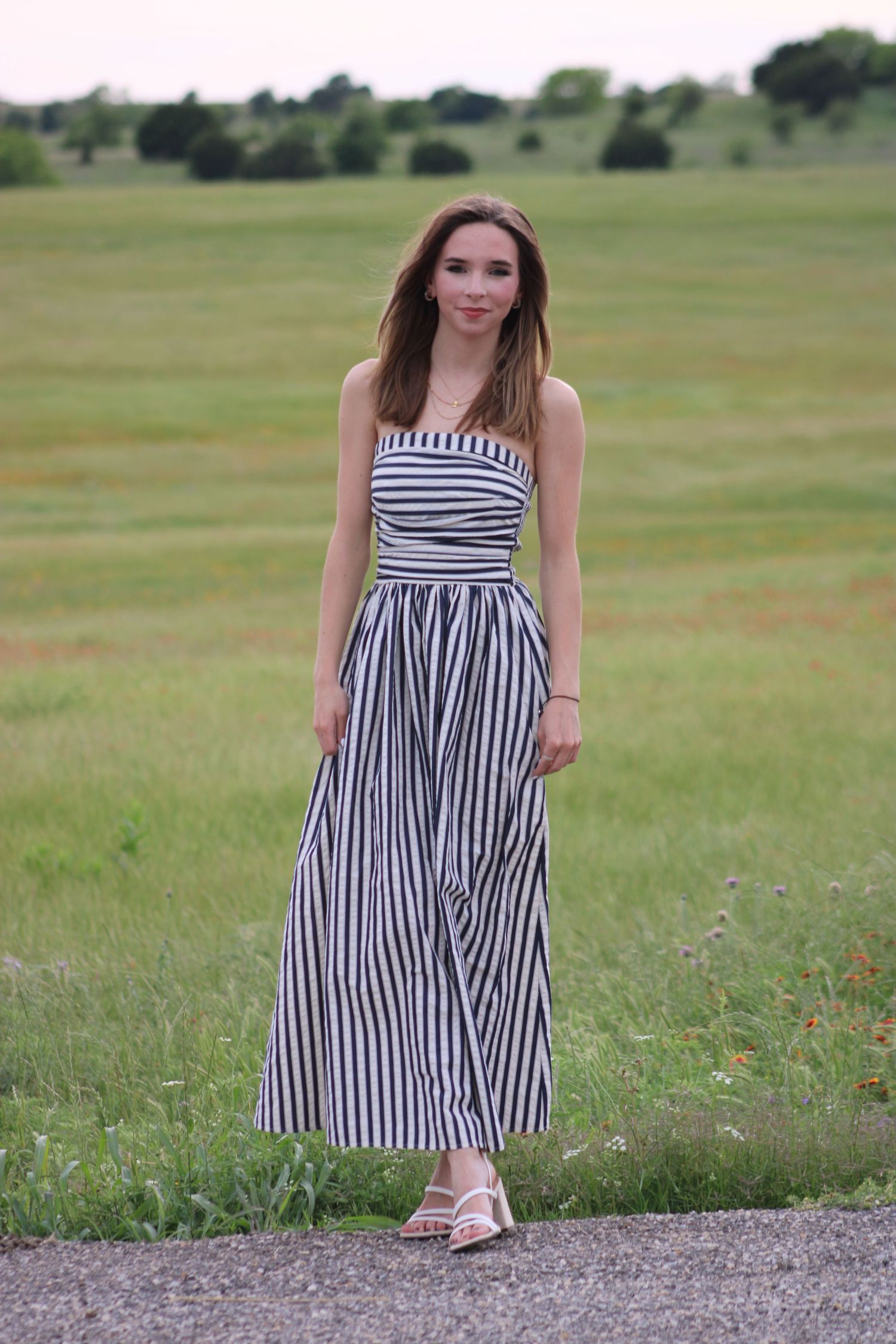 A black and white striped sundress photographed outdoors in a grassy field.