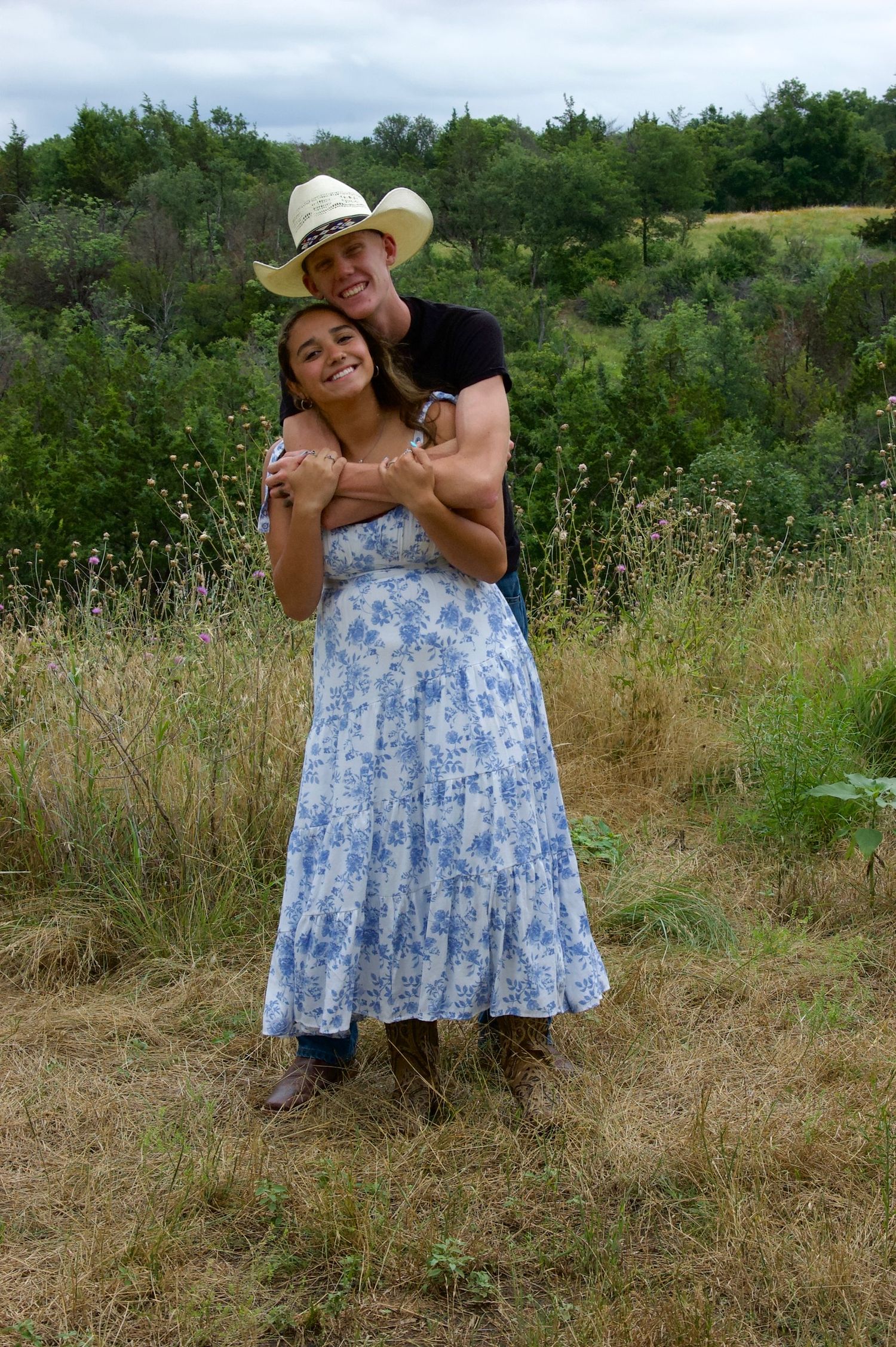 Summer countryside photoshoot wearing blue floral dress and cowboy hat.