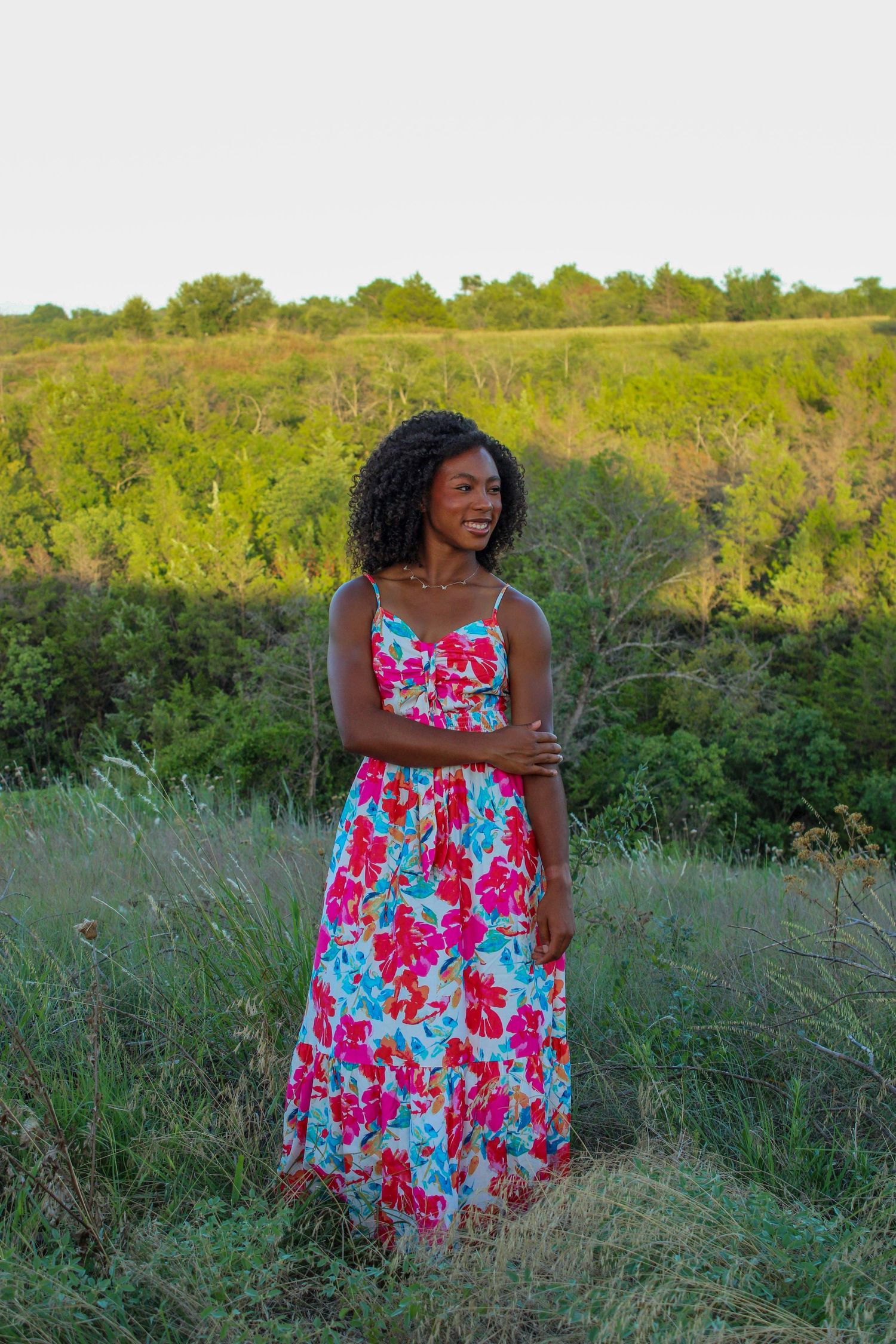 Woman in floral dress poses gracefully in a summer meadow.