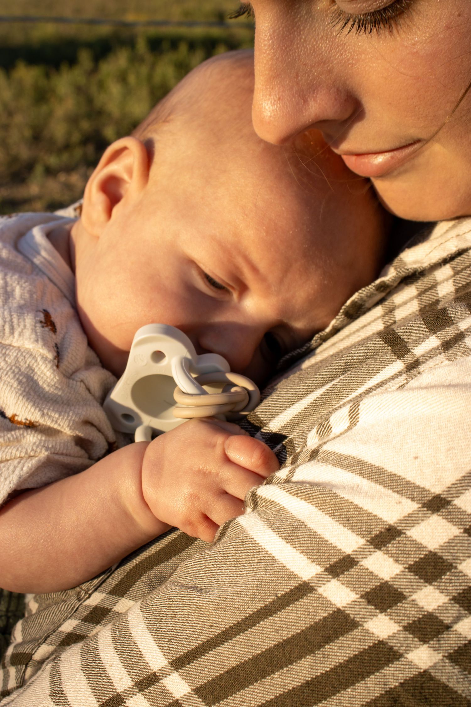 Close-up view of someone sleeping peacefully on a plaid blanket in warm sunlight.
