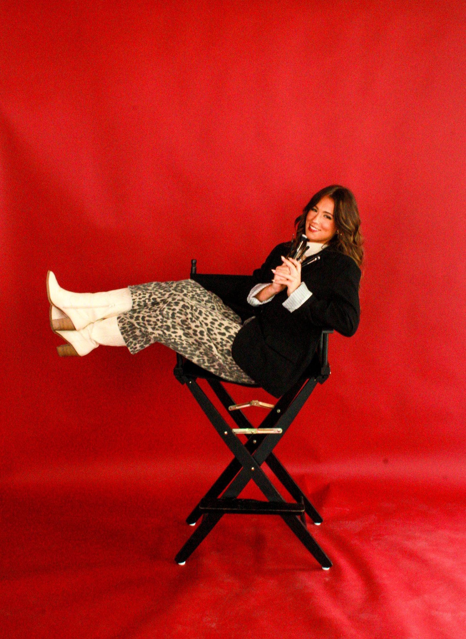 Woman in black outfit reclining on red backdrop during creative portrait photography session.