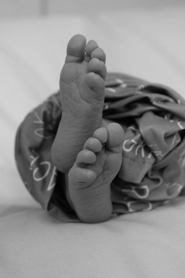 Close-up black and white photos of tiny baby feet wrapped in soft fabric.