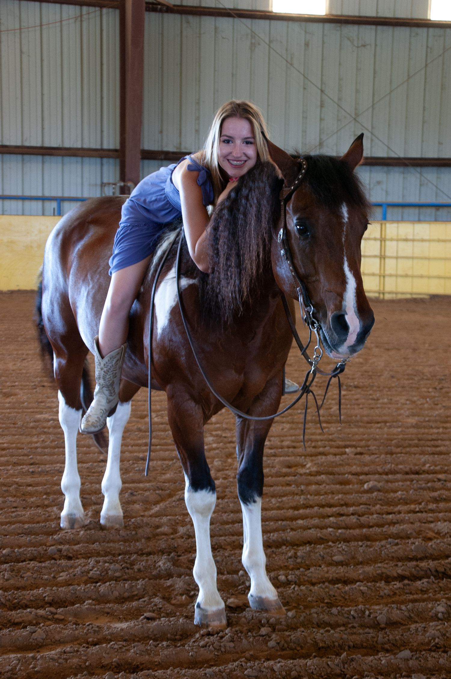 Brown and white horses being led inside a training arena.