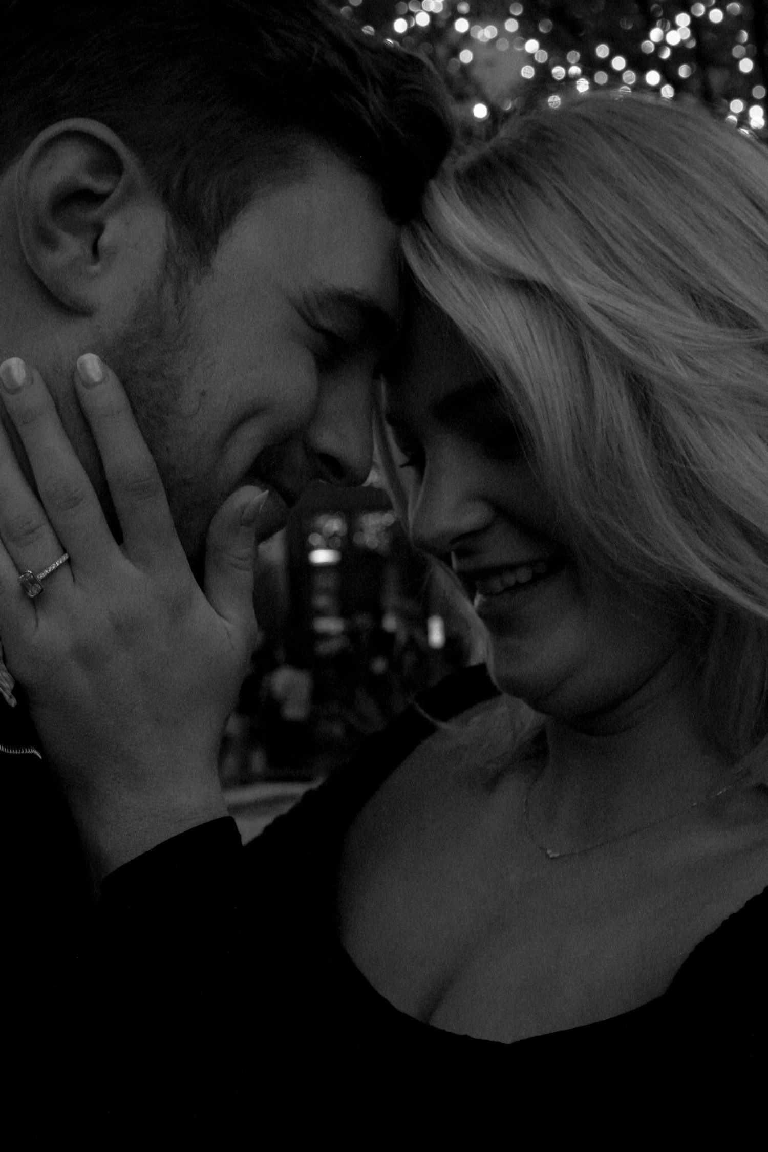 A romantic couple shares an intimate moment under twinkling lights in a series of black and white photographs.