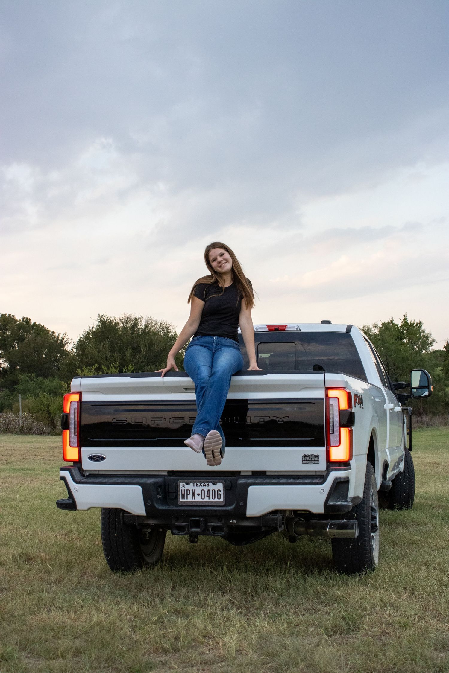 A modern silver pickup truck parked in an open field during sunset.