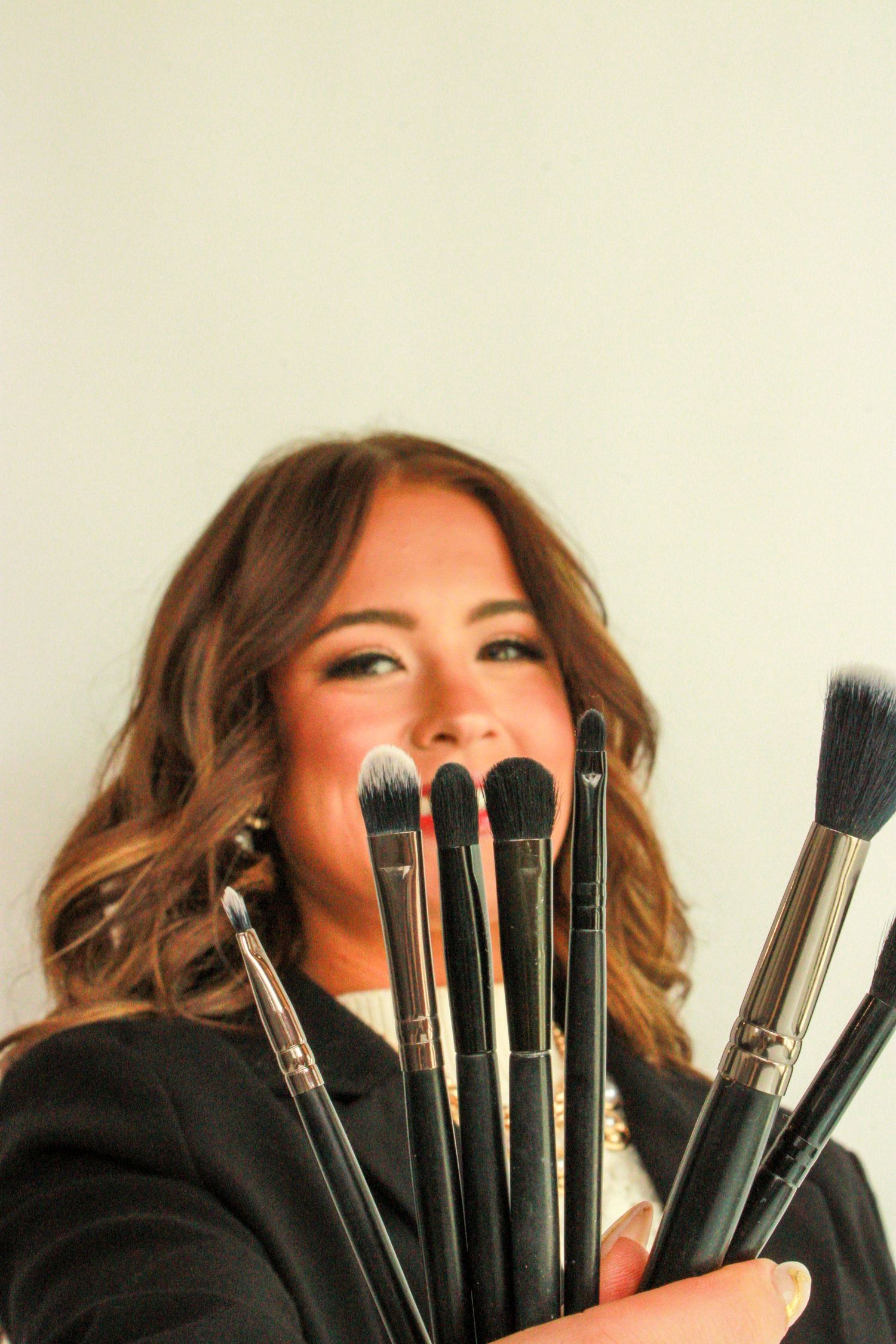 A series of four photos showing makeup brushes held up in front of a person wearing black against a white background.