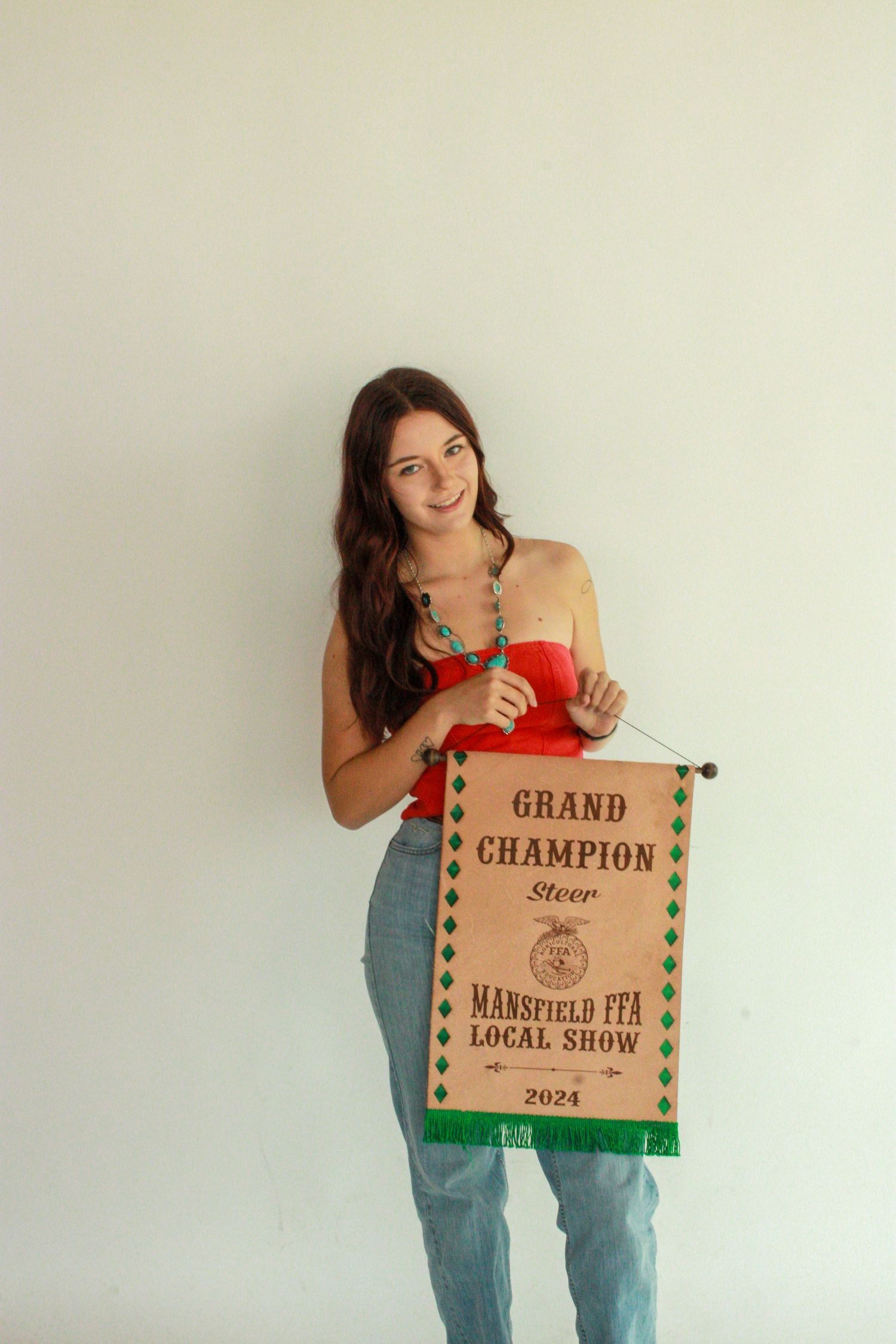 A series of photos showing someone in blue jeans holding up a brown paper champion award banner.