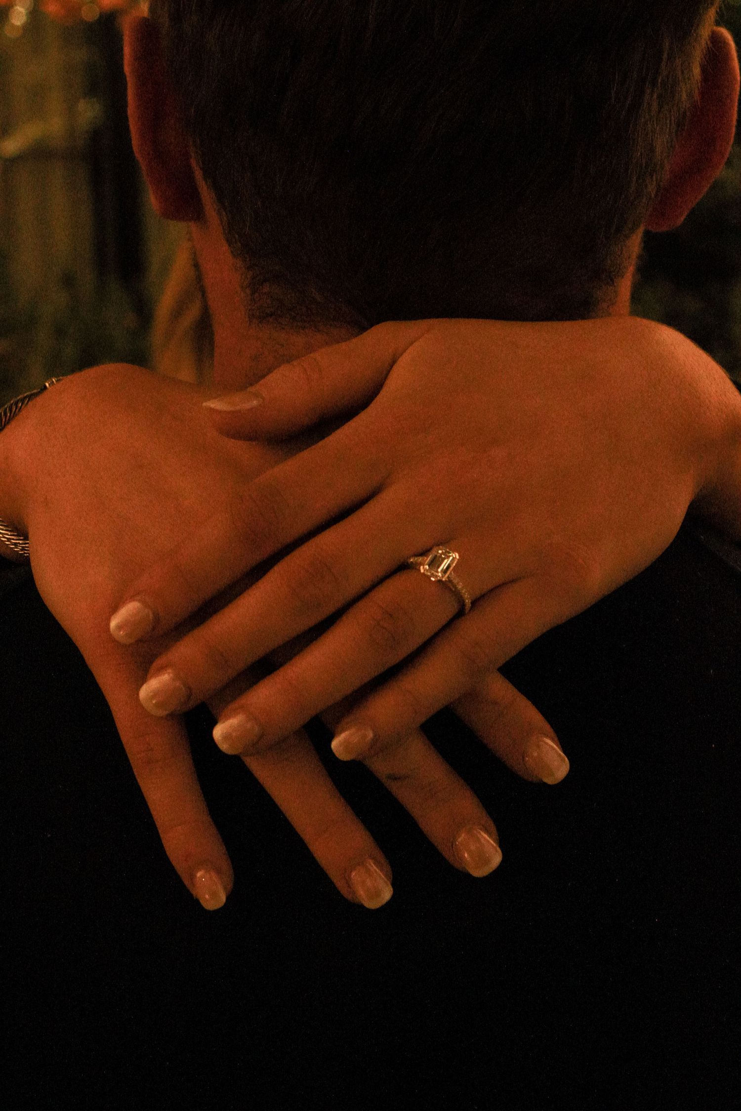 Close-up sequence of hands displaying an engagement ring from different angles in warm lighting.