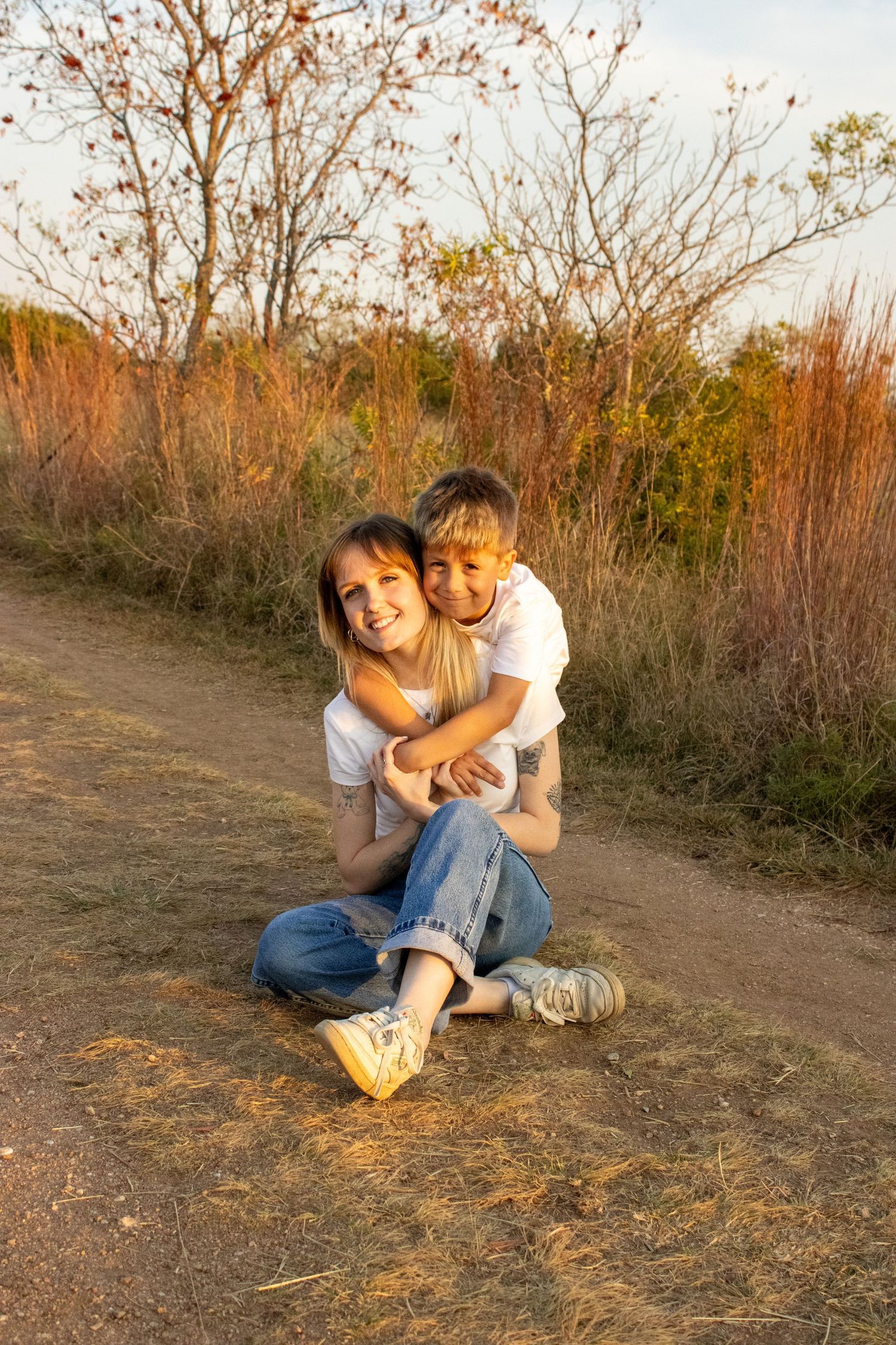 Playful family moments captured in warm sunlight on a dirt path surrounded by autumn foliage.