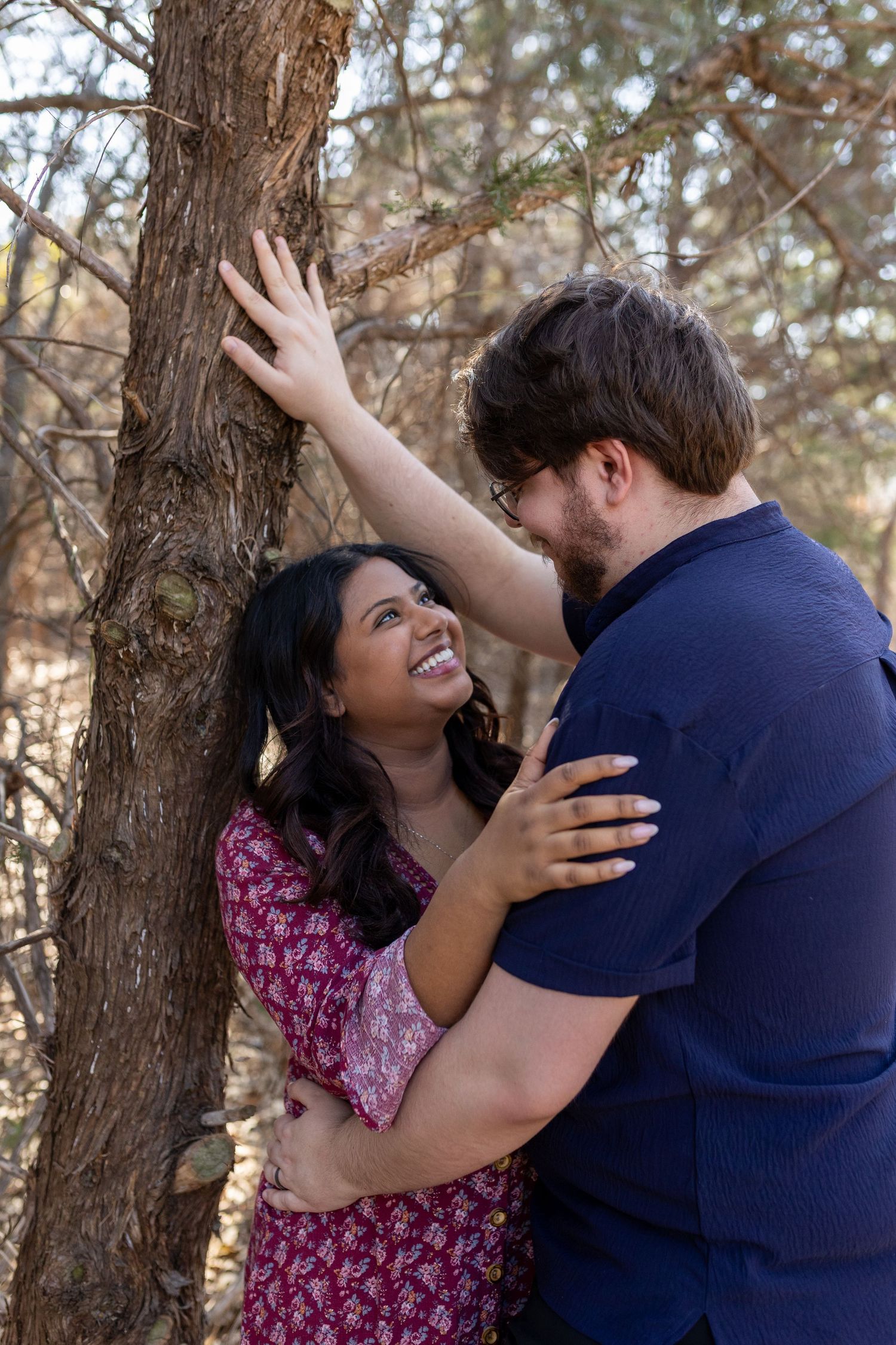 A romantic couple shares tender moments against a tree trunk in a series of progressive intimate poses.