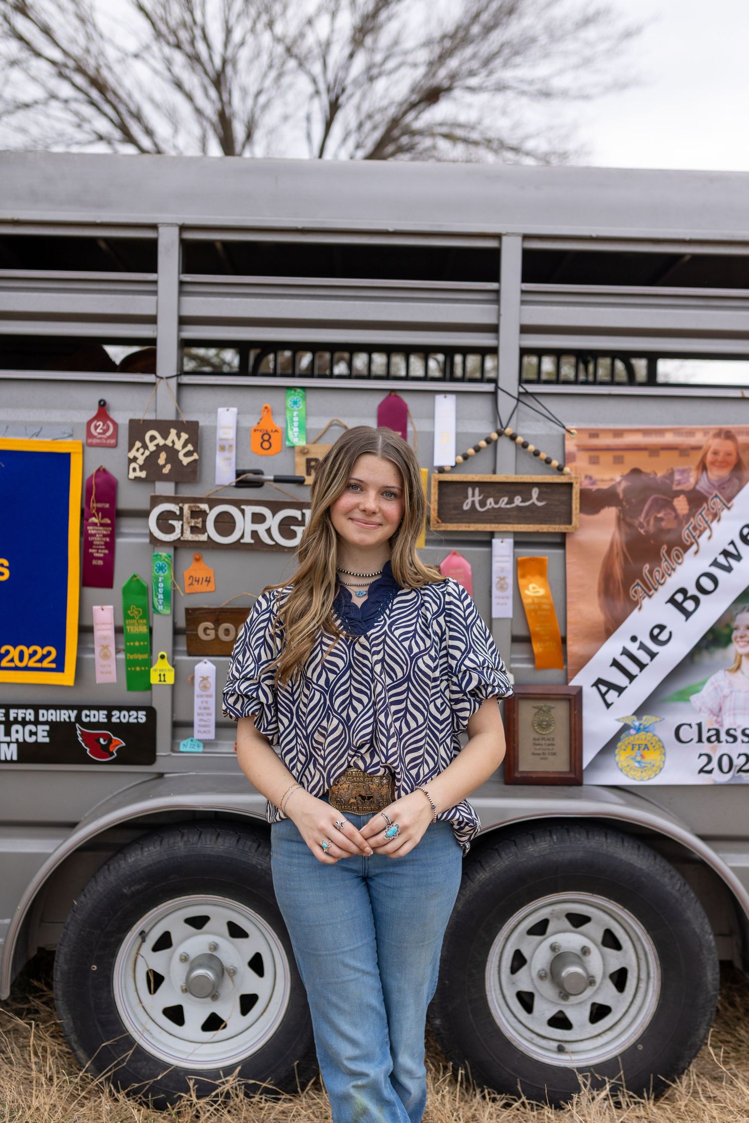 A decorated livestock trailer with stickers and banners showcasing achievements and awards.