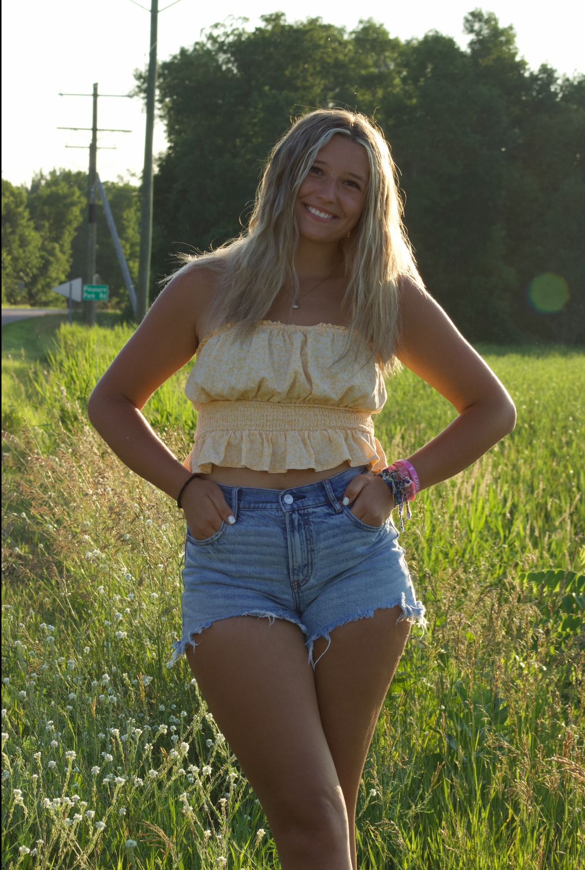 Summer photoshoot in a wildflower field at golden hour wearing denim shorts and ruffled top.