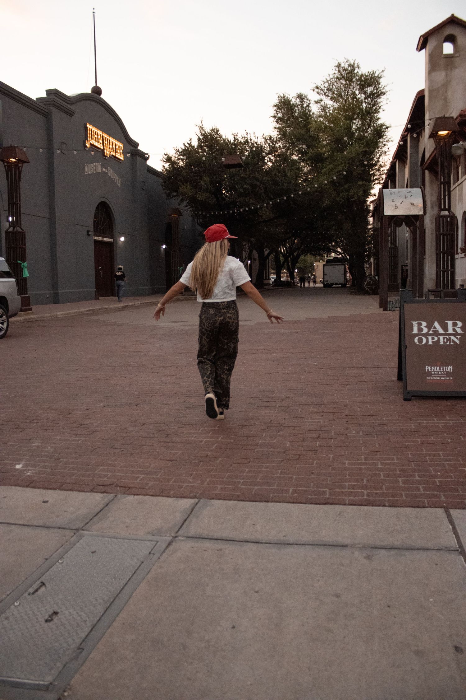 People walking across brick paved plaza at dusk.