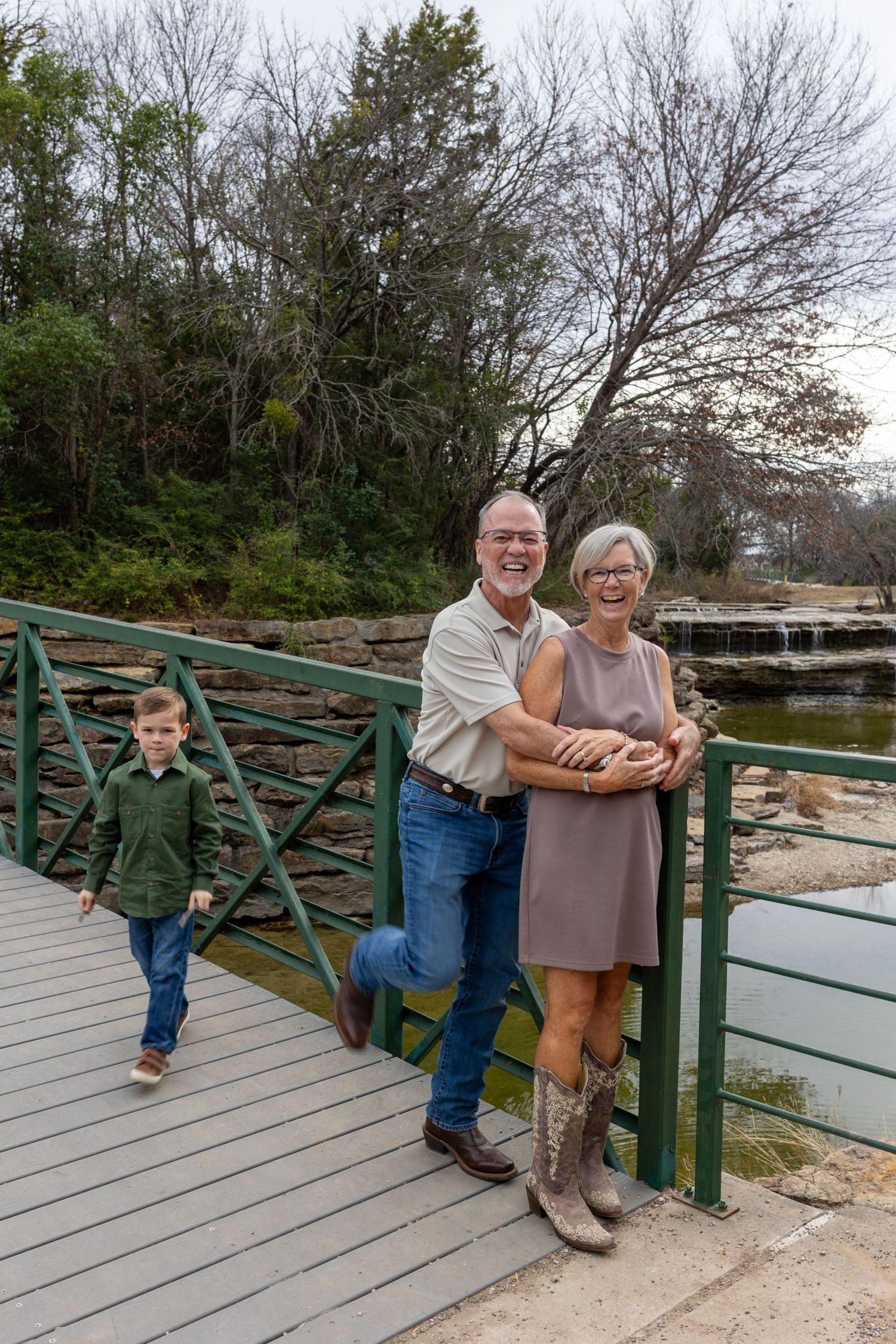 People standing together on a wooden deck overlooking a pond on an overcast day.