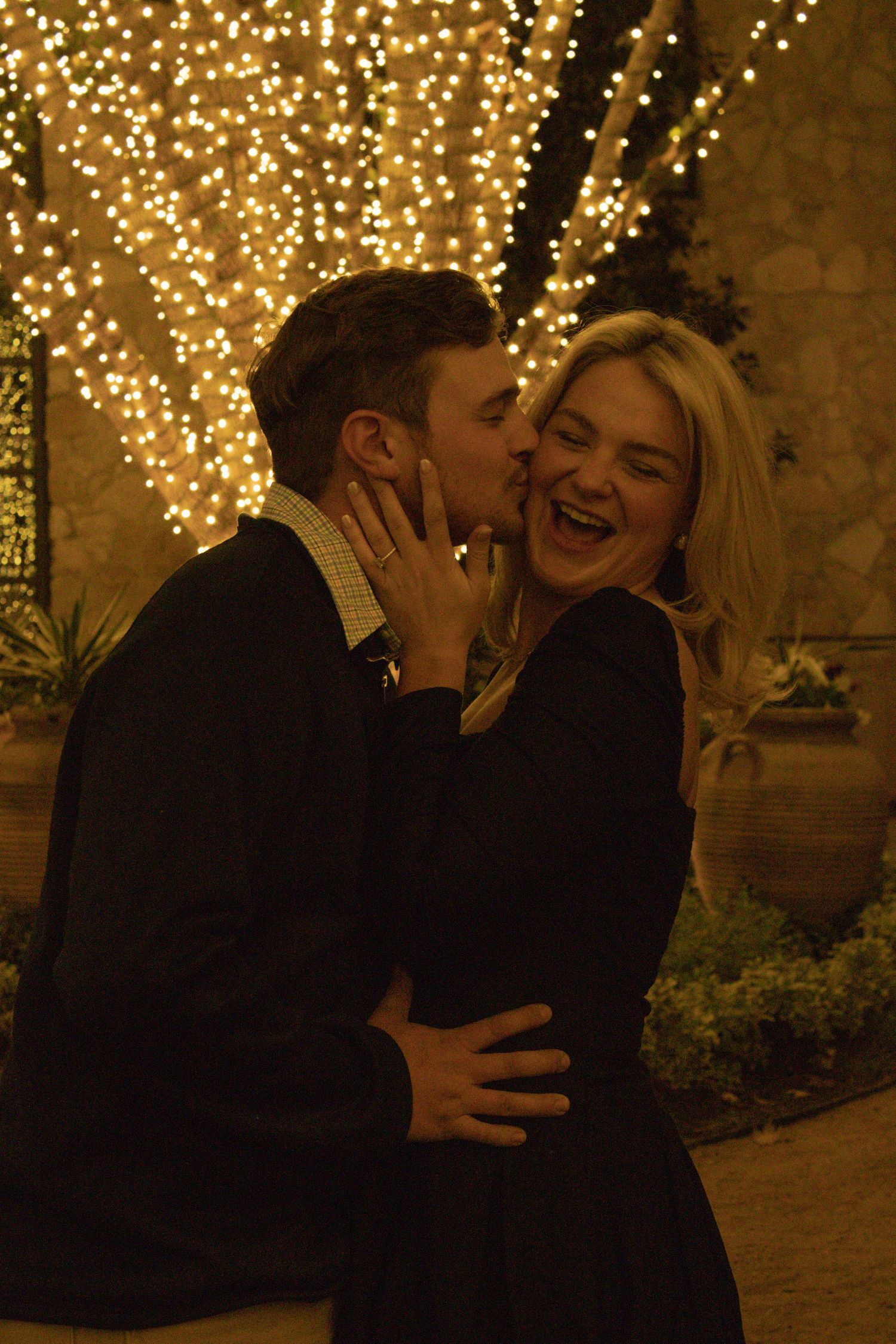 A romantic evening moment captured with twinkle lights creating a warm ambiance in the background.
