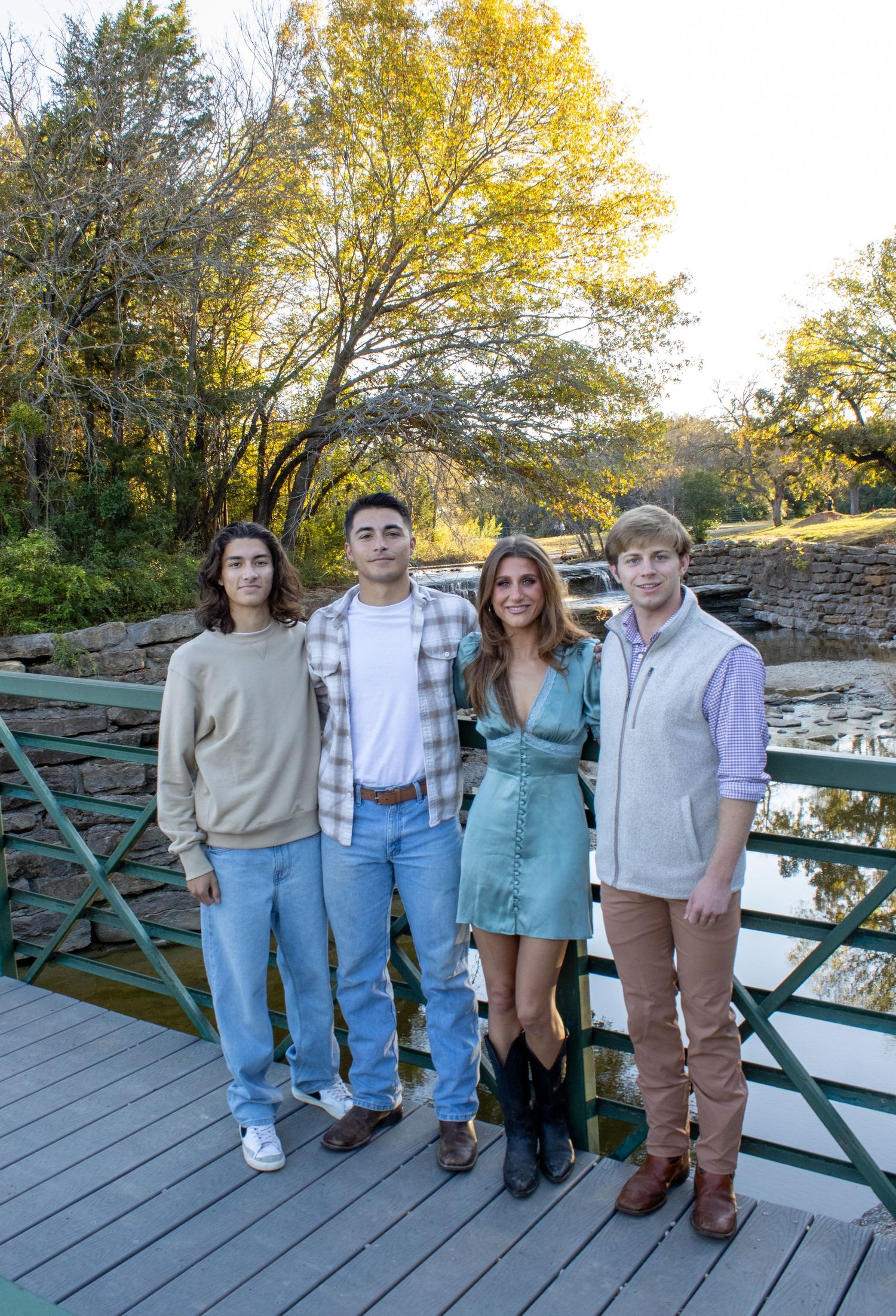 Group stands together on wooden deck surrounded by autumn trees with golden yellow foliage in background.