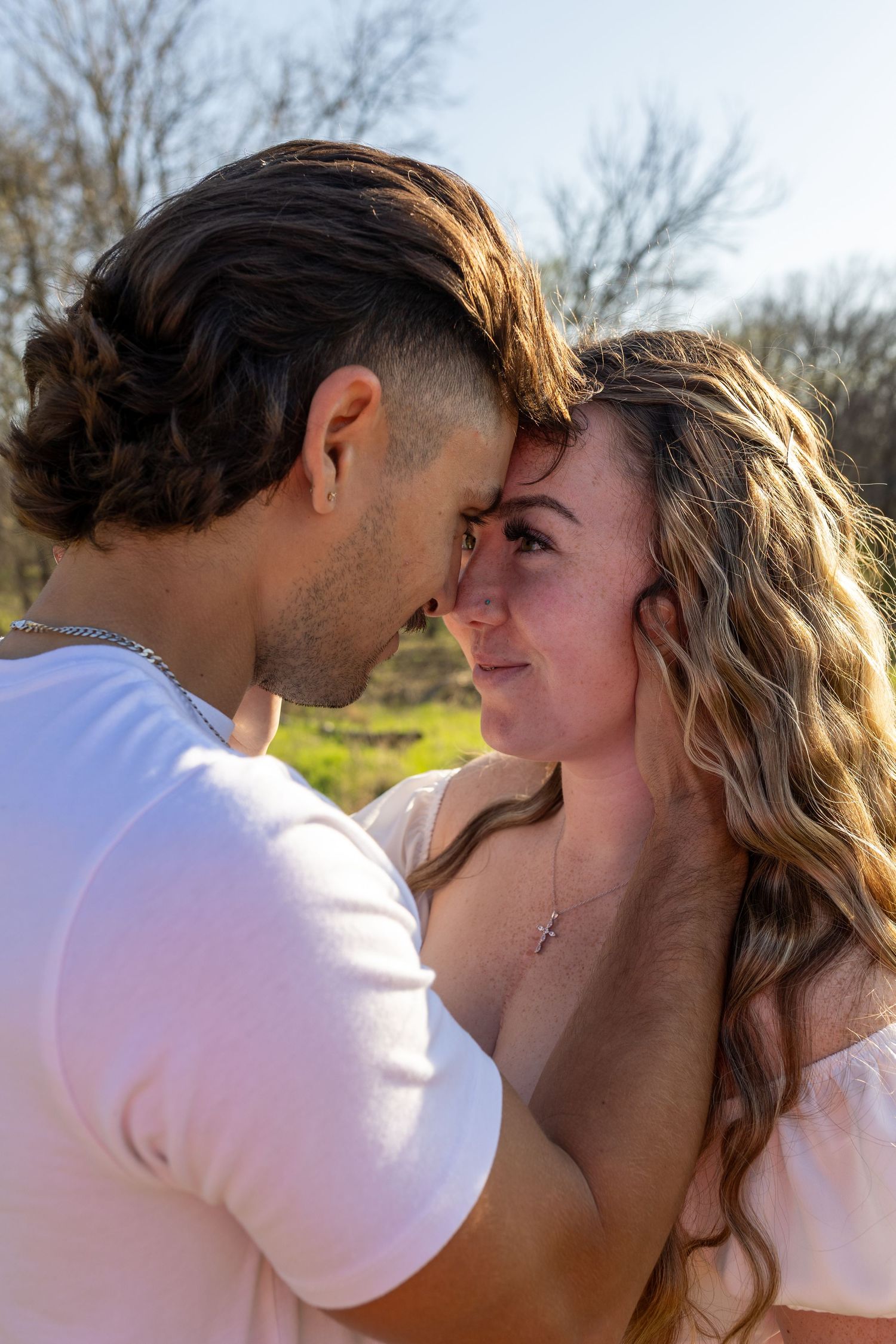A romantic couple in white clothing share an intimate moment in a series of close-up photos outdoors.