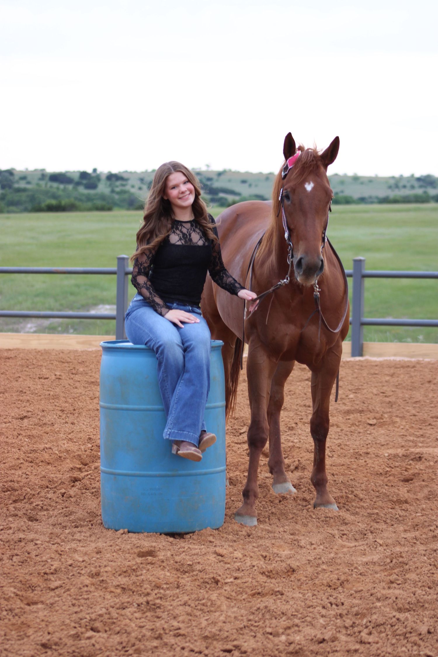 Training session with horse and blue barrel in sandy arena.