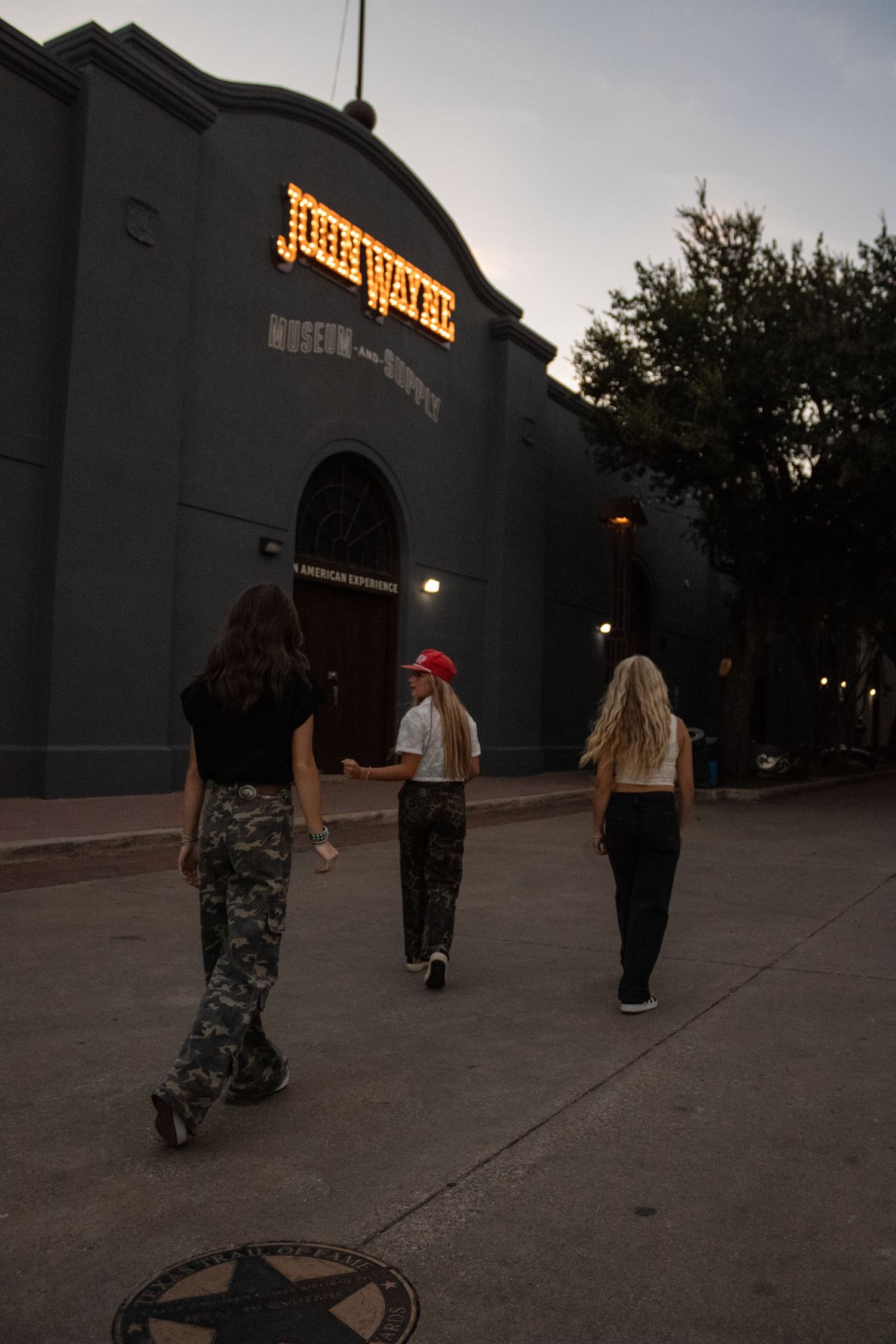 Group walking at dusk near illuminated storefront signs.