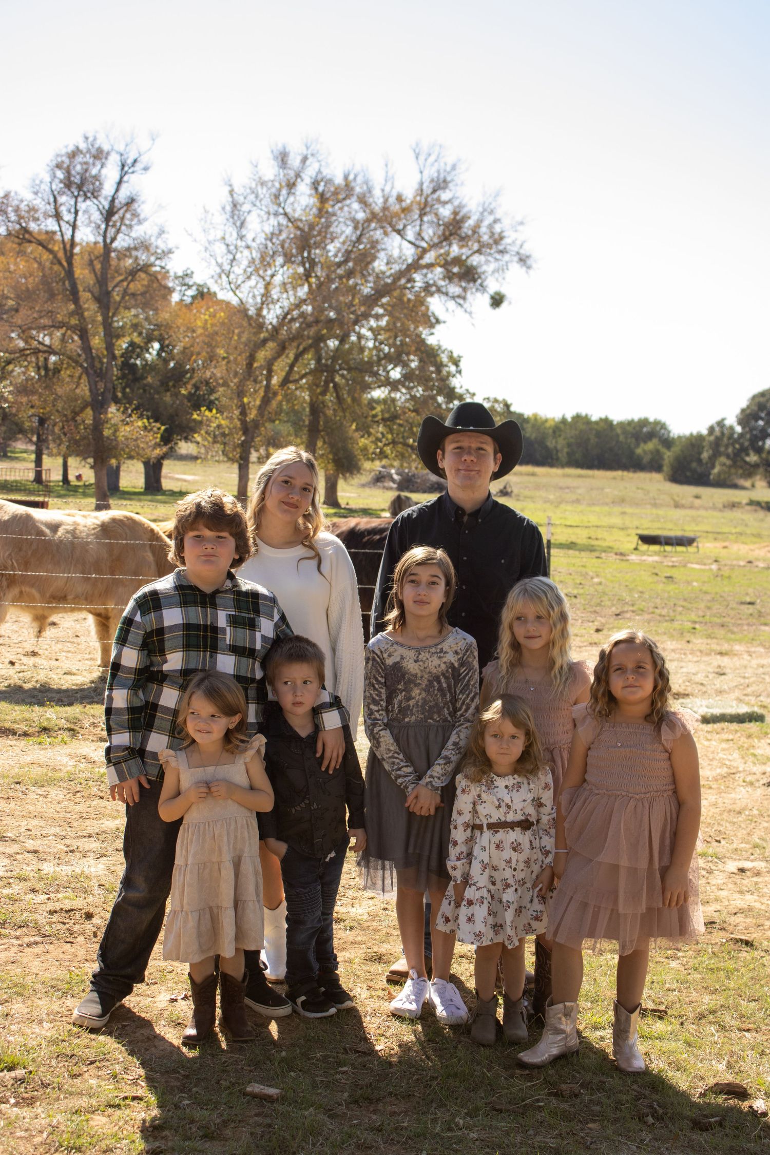 A group poses together outdoors on a sunny autumn day with bare trees and a field in the background.