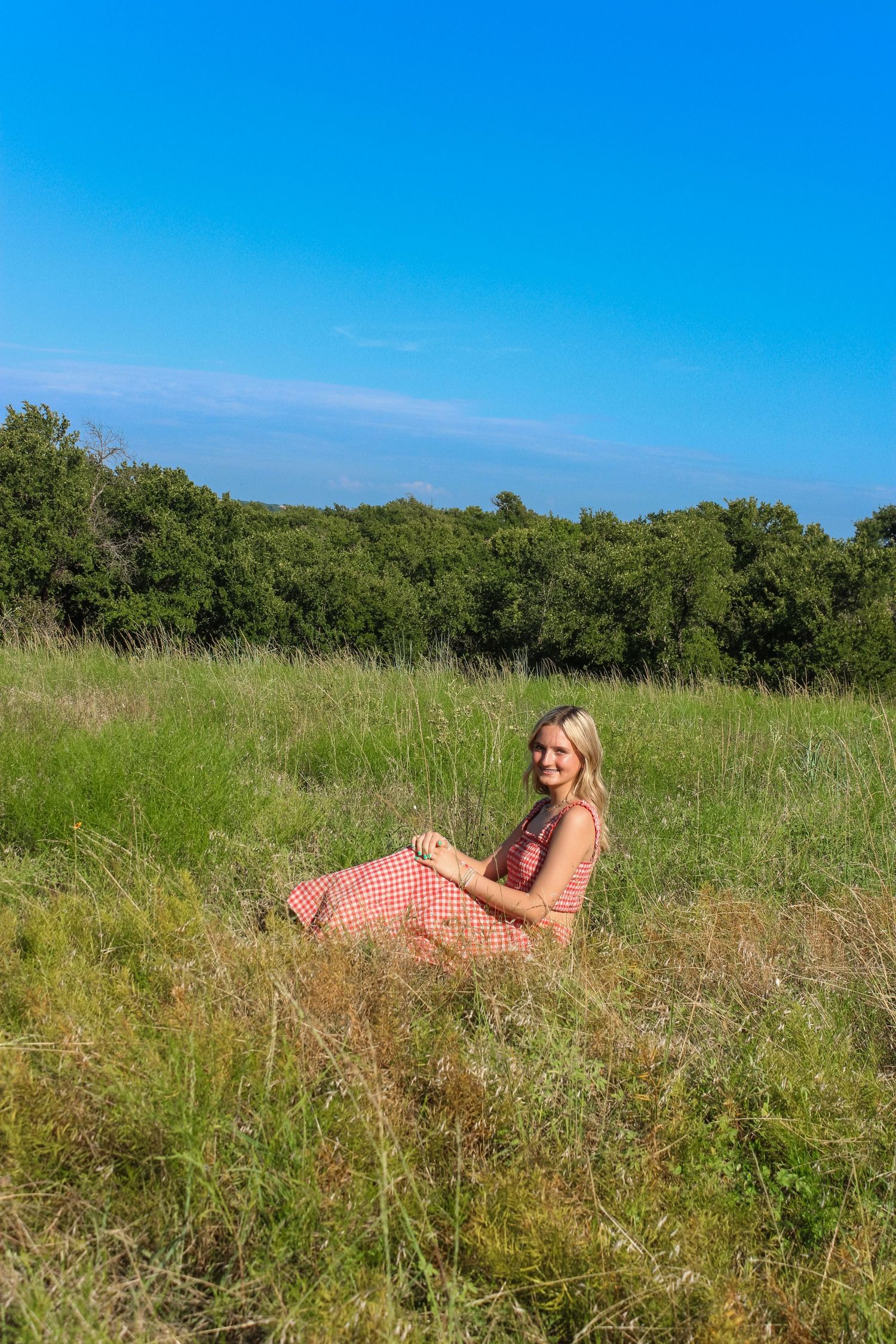 Person in pink dress reclining in summer meadow.