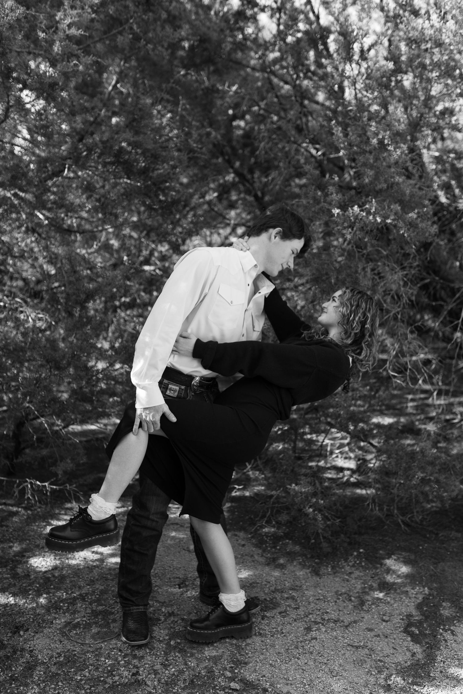 Black and white photo sequence showing a playful dance dip movement outdoors with trees in background.