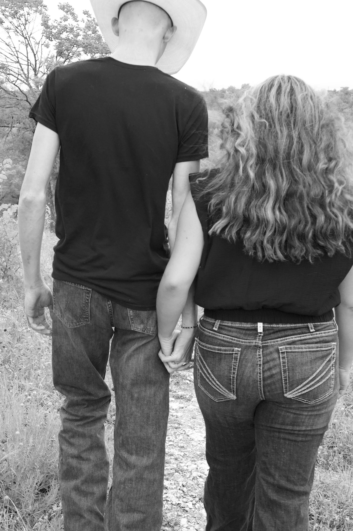 Black and white photo of couple in matching dark outfits from behind.