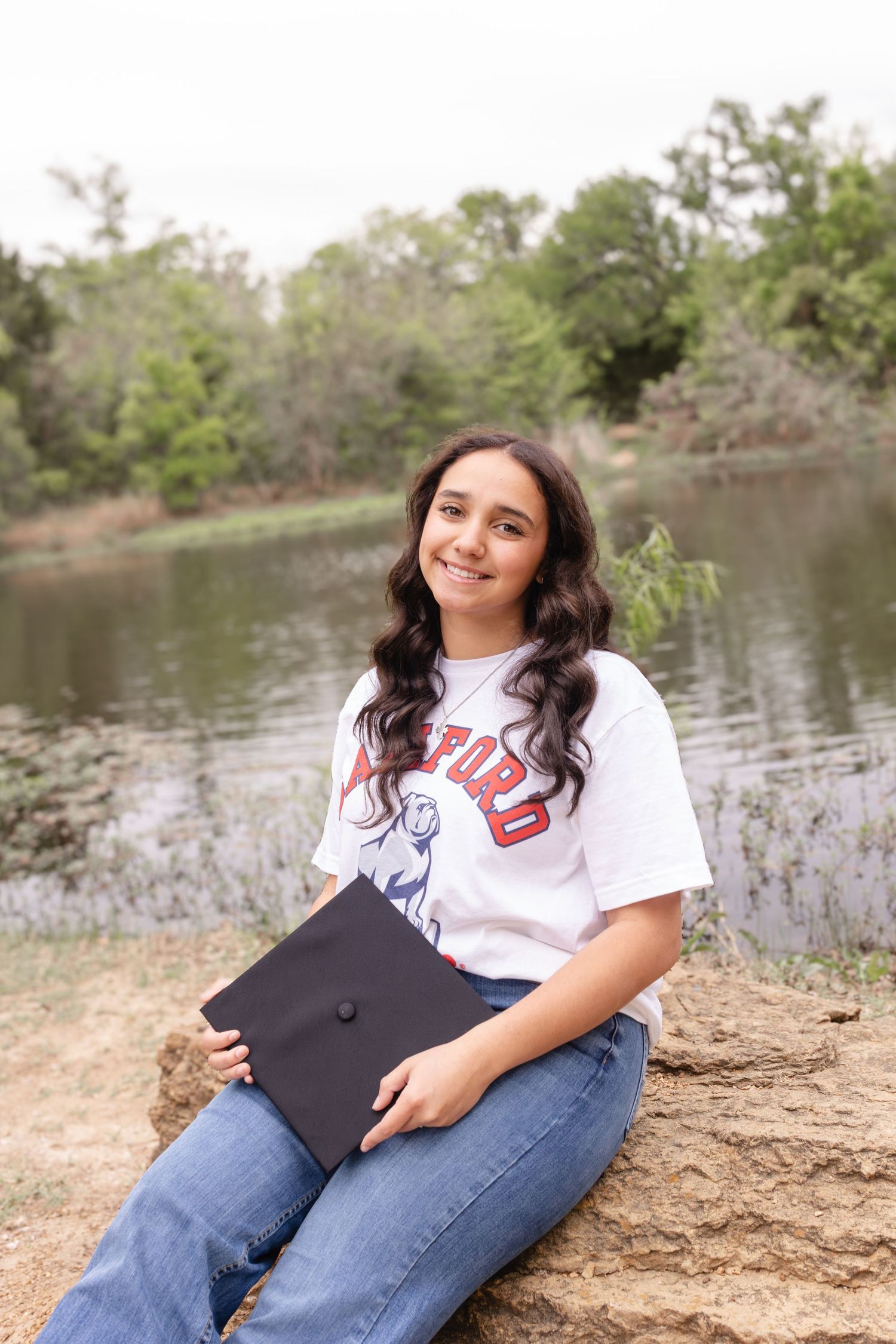 Relaxed outdoor portrait session by a lake with casual attire including denim and graphic tee.