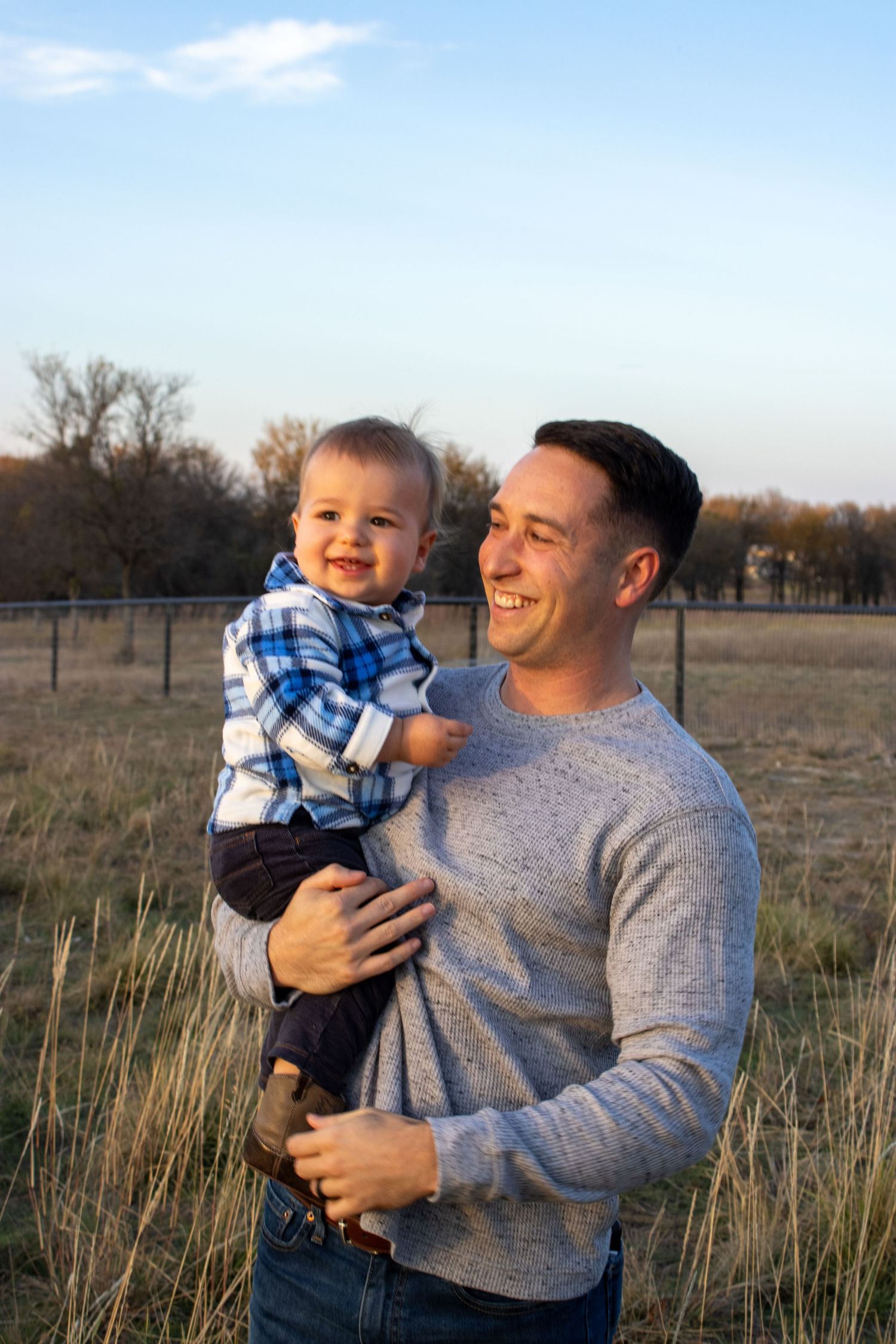 A heartwarming outdoor scene shows a parent and child sharing joyful moments together in a rural field at sunset.