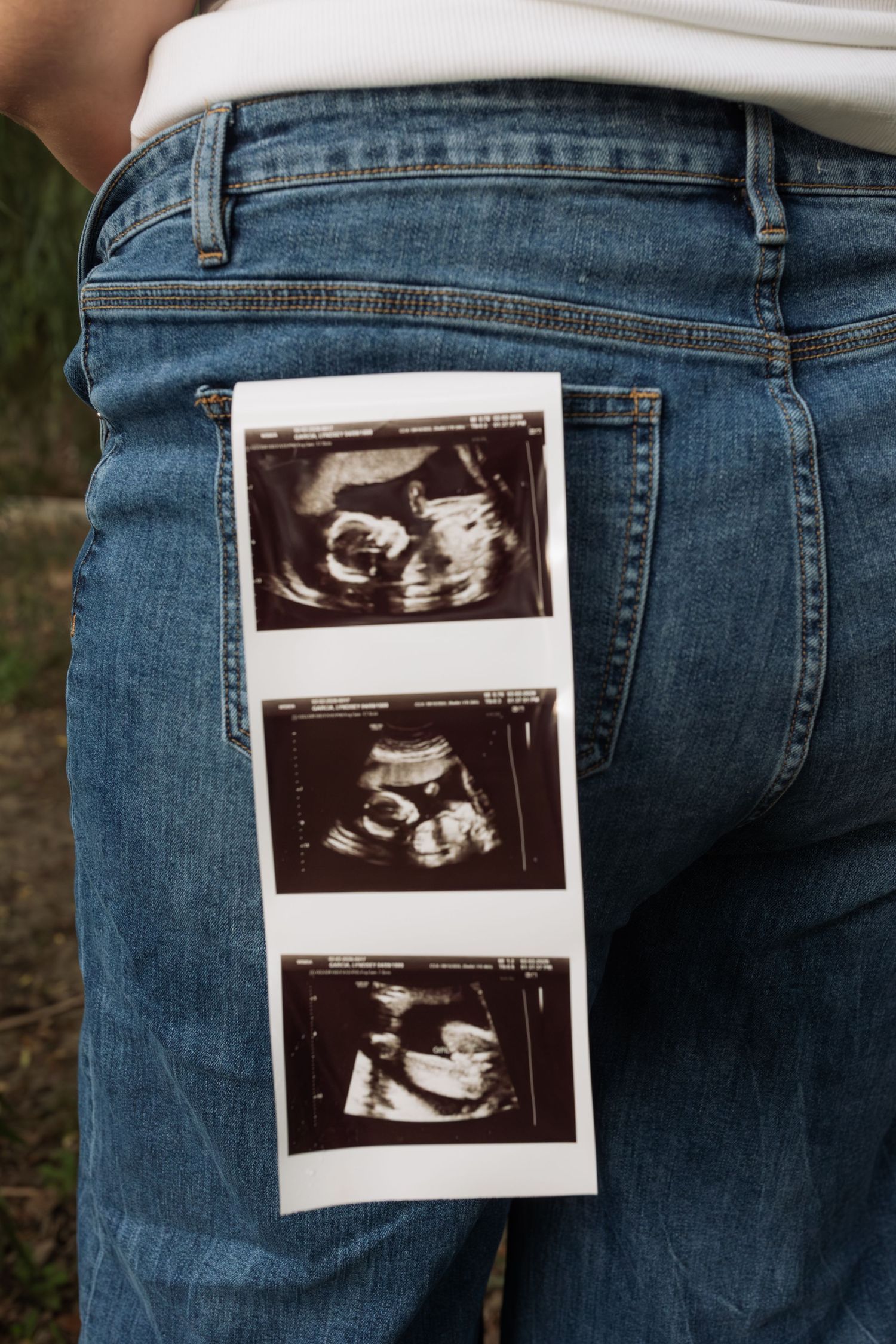 Ultrasound photos tucked in back pocket of blue jeans, pregnancy announcement concept.