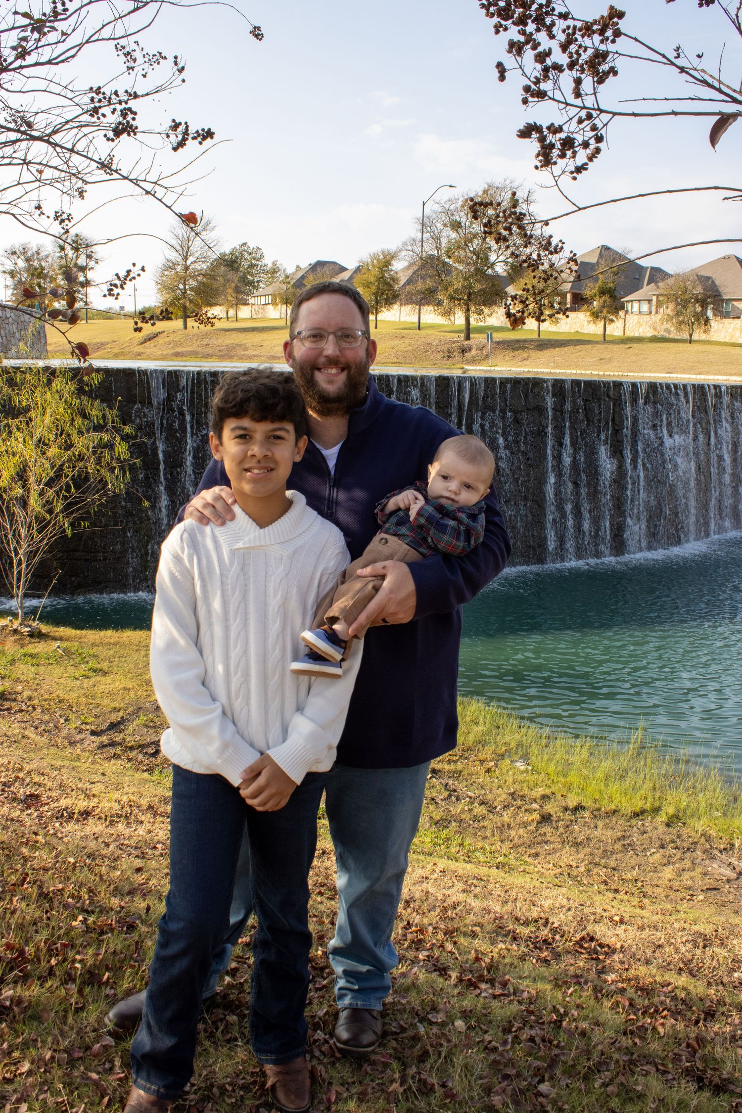 Family spending time together outdoors near a scenic waterfall on a sunny afternoon.