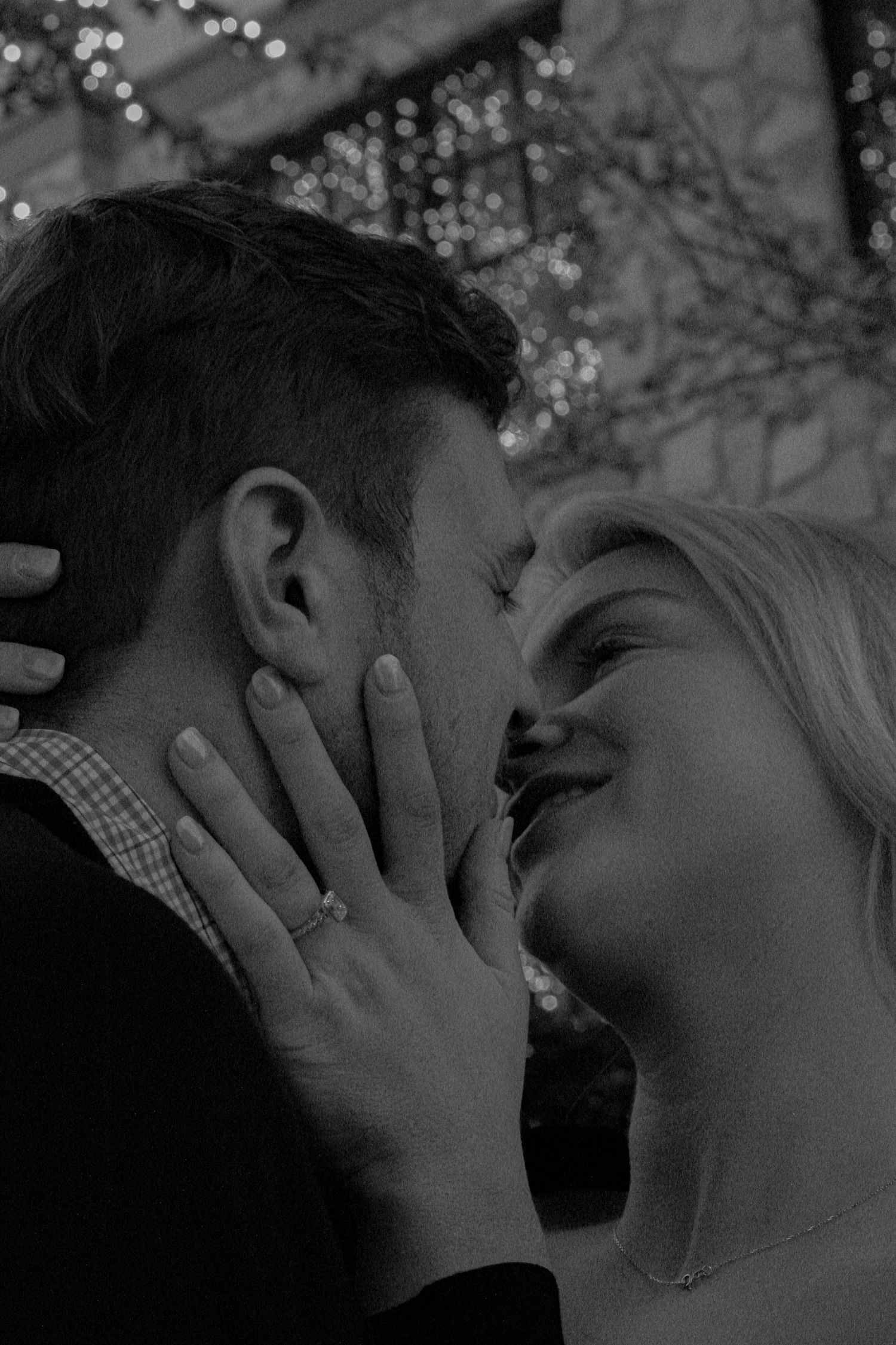 A romantic black and white sequence showing a couple sharing intimate kisses with soft bokeh lighting in the background.