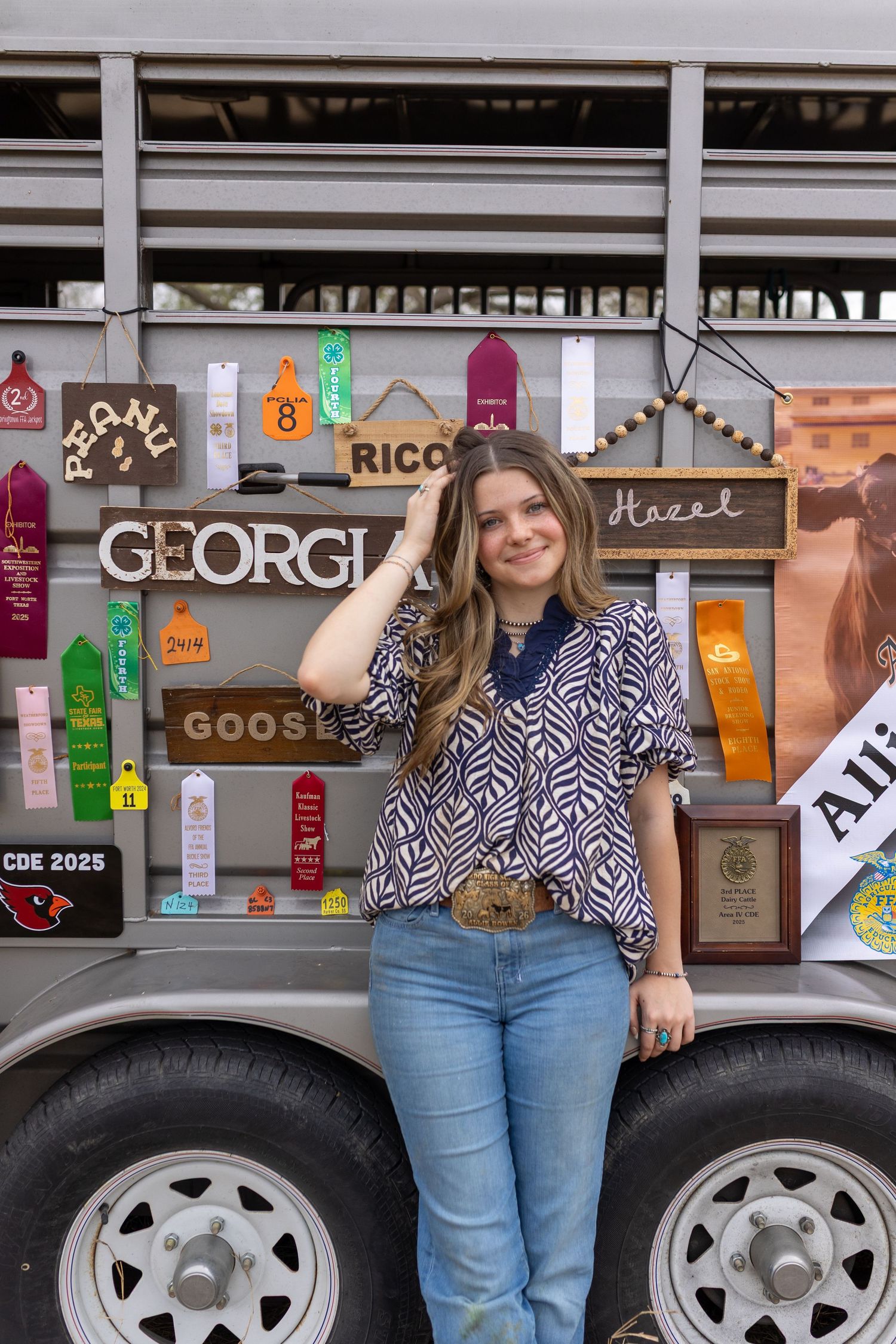 A person in blue jeans and a patterned shirt poses beside a white food truck with colorful signage.