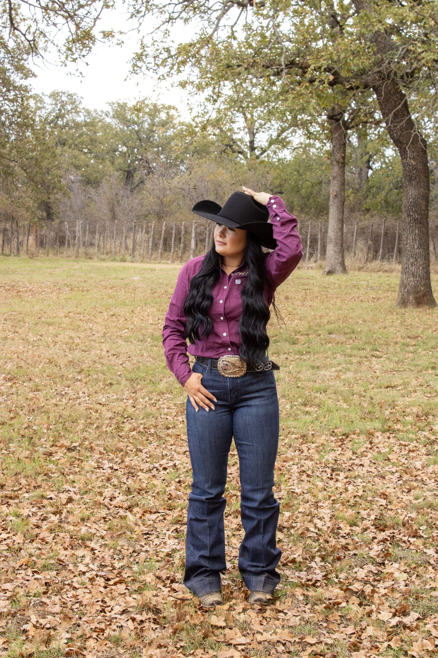 A western-style outfit featuring a purple button-up shirt and blue jeans on a fall day with scattered leaves.